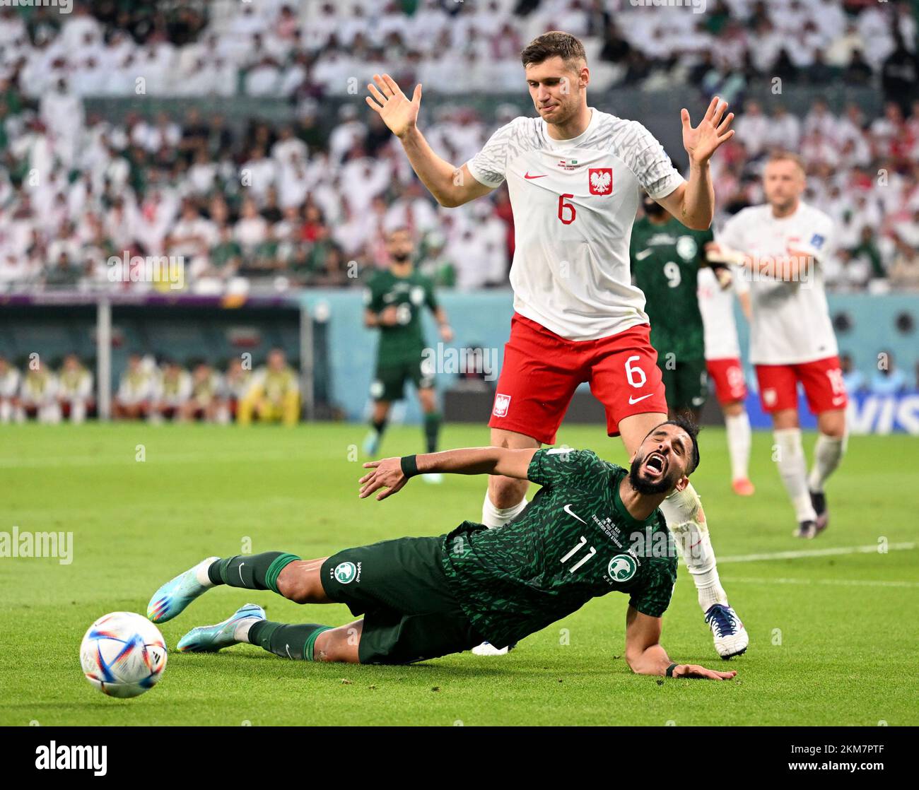 Al Rayyan, Qatar. 26th Nov, 2022. Krystian Bielik (top) of Poland reacts after fouling to Saleh Alshehri of Saudi Arabia in the penalty area during the Group C match between Poland and Saudi Arabia at the 2022 FIFA World Cup at Education City Stadium in Al Rayyan, Qatar, Nov. 26, 2022. Credit: Xia Yifang/Xinhua/Alamy Live News Stock Photo