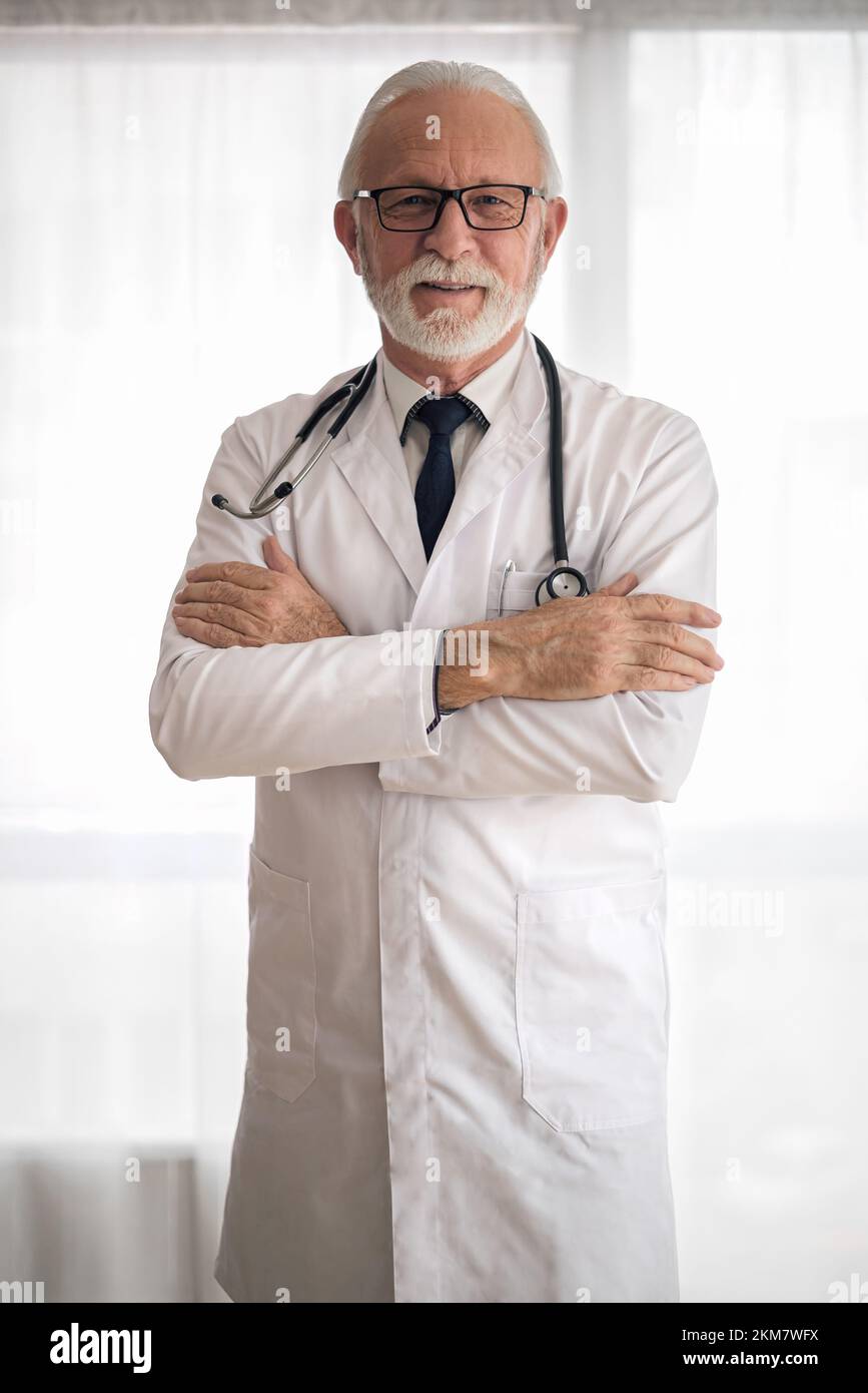 Picture of confident bearded hospital worker, standing cross-armed at the clinic. Stock Photo