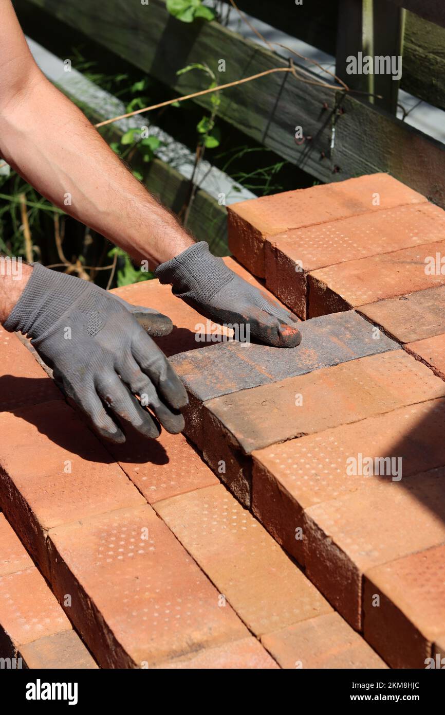 Man's hand holding red brick. Construction and building works concept. House renovation in process. Stock Photo