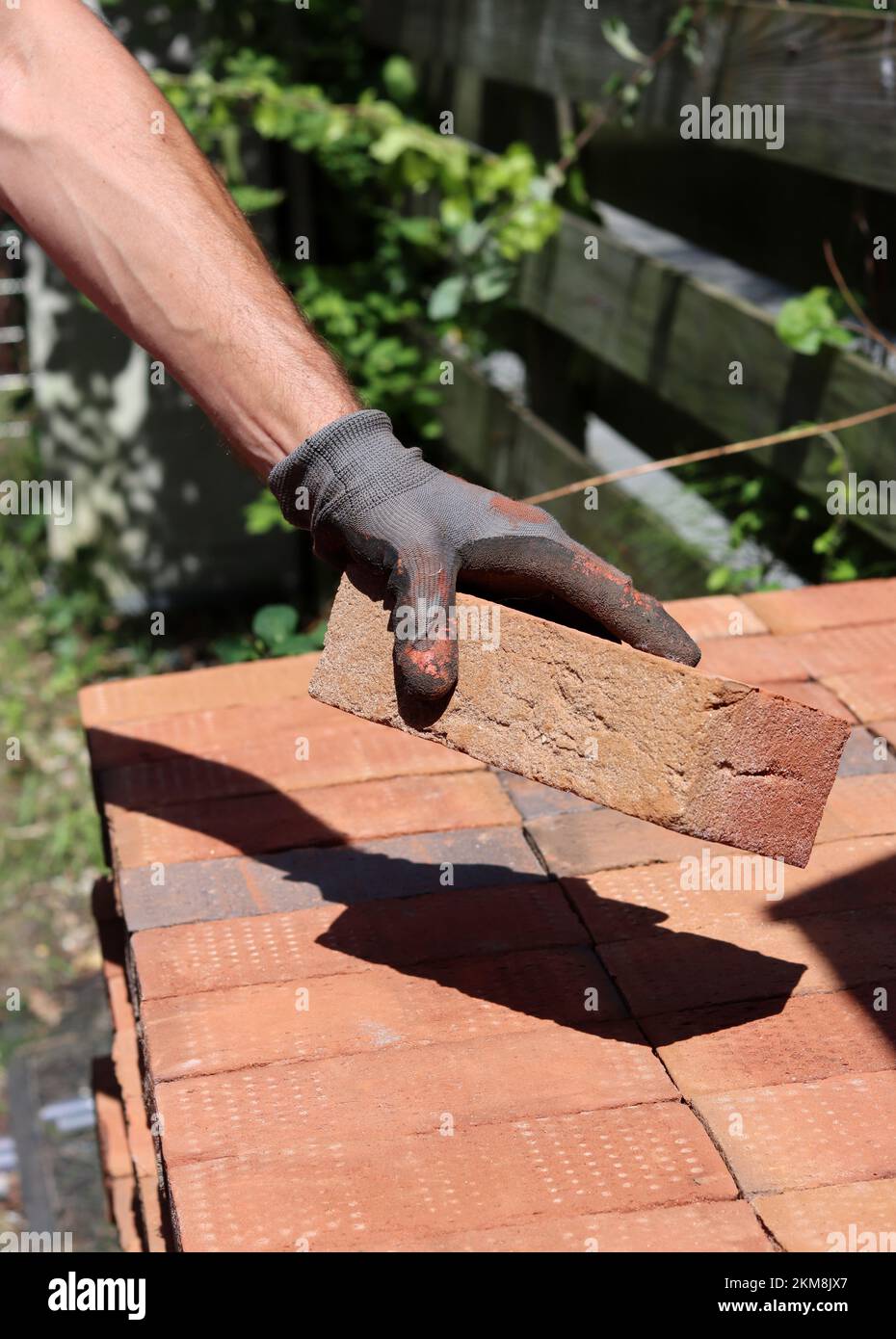 Man's hand holding red brick. Construction and building works concept. House renovation in process. Stock Photo