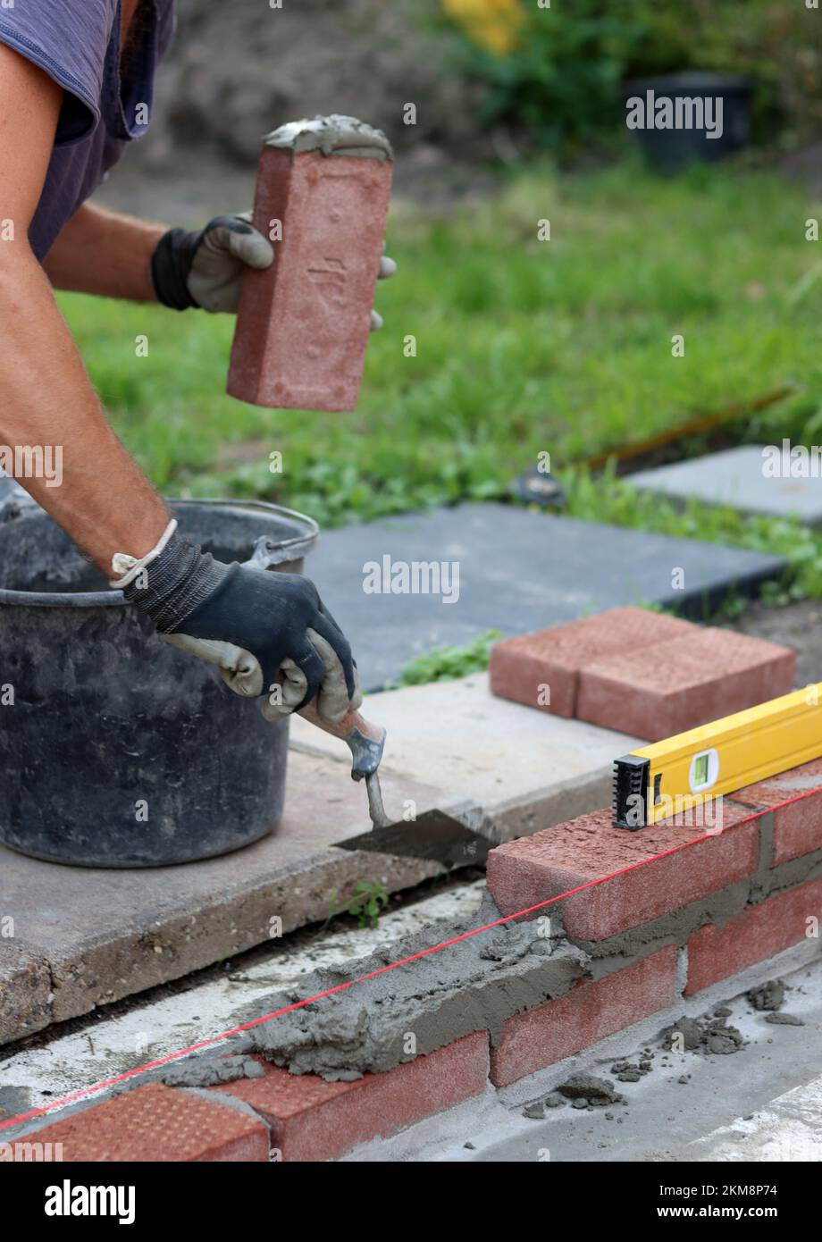 Construction work in progress. Male builder working with red bricks. Masonry wall close up photo. Stock Photo