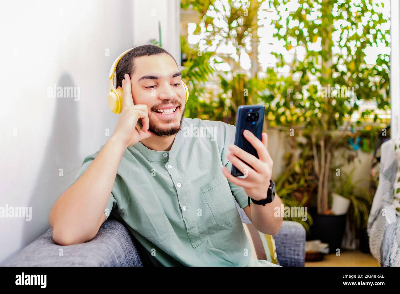 A closeup of a happy, relaxed man at home using a phone sitting on the sofa Stock Photo