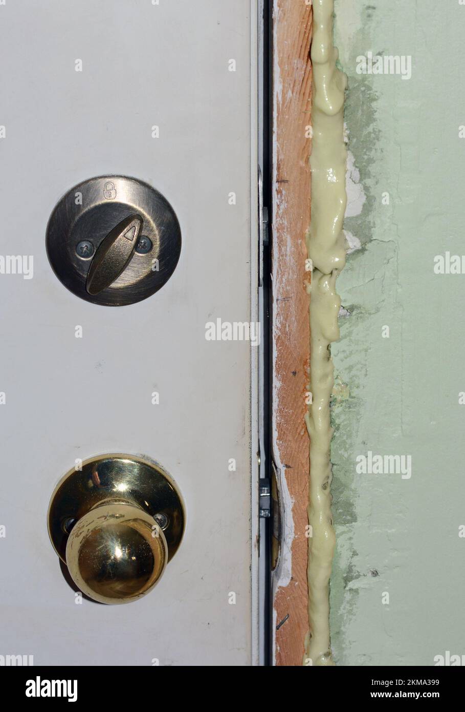 Expanding spray foam insultation is used to fill the cracks around an exterior door in an older construction remodeling project. Stock Photo