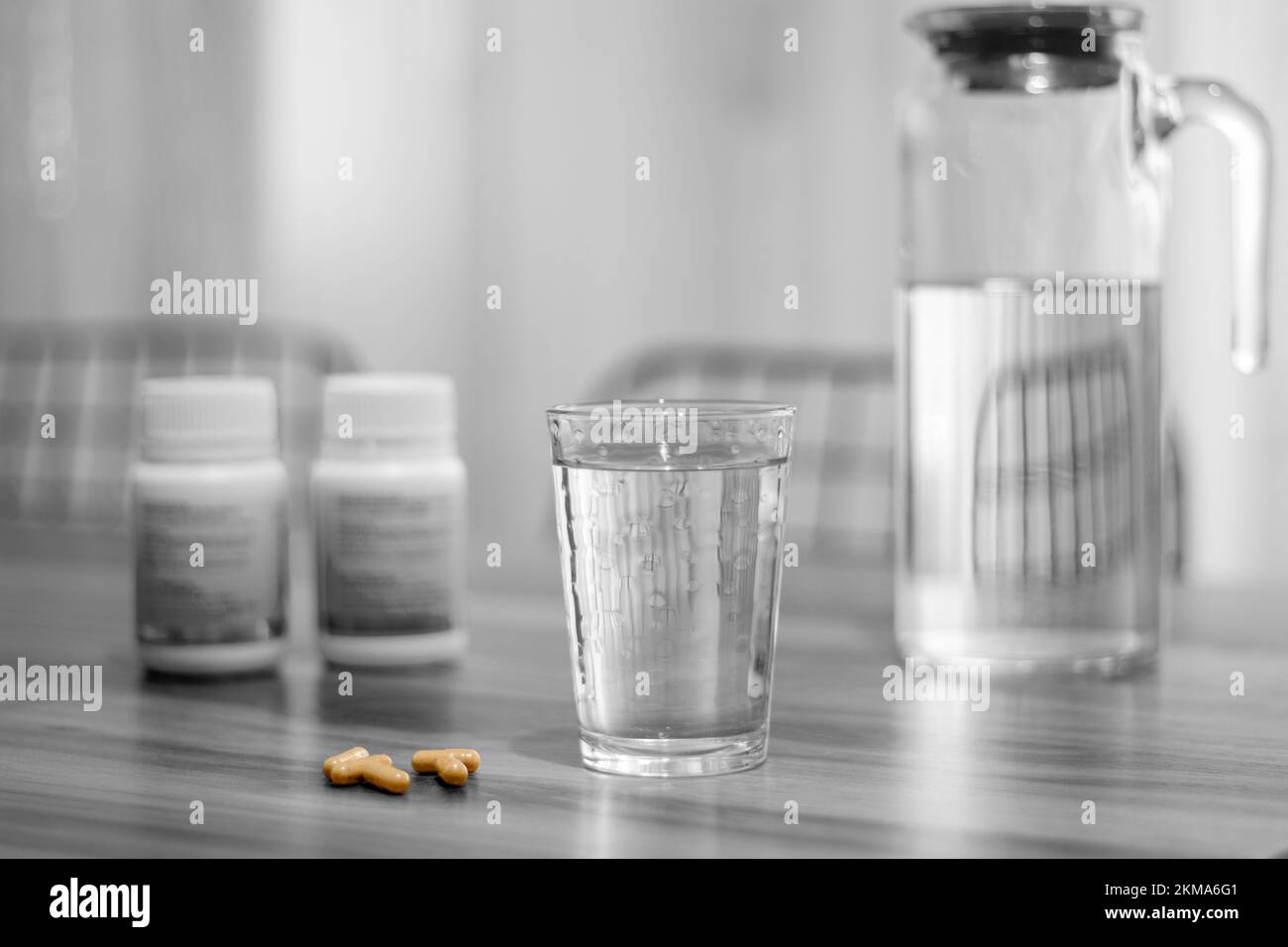 Pill capsule medicine and glass of water on black and white background