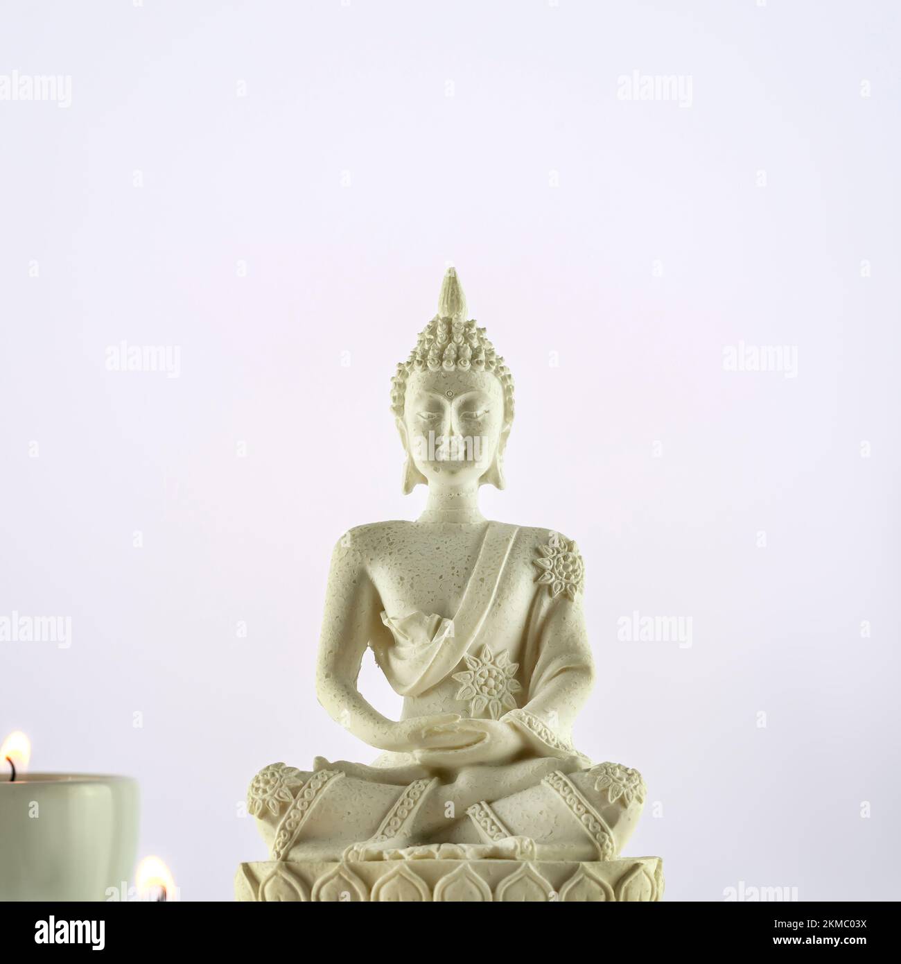 Buddhism composition with white Buddha statue and candles on a light gradient background. Vesak, Buddha Day. Mental health, relax, yoga and meditation Stock Photo