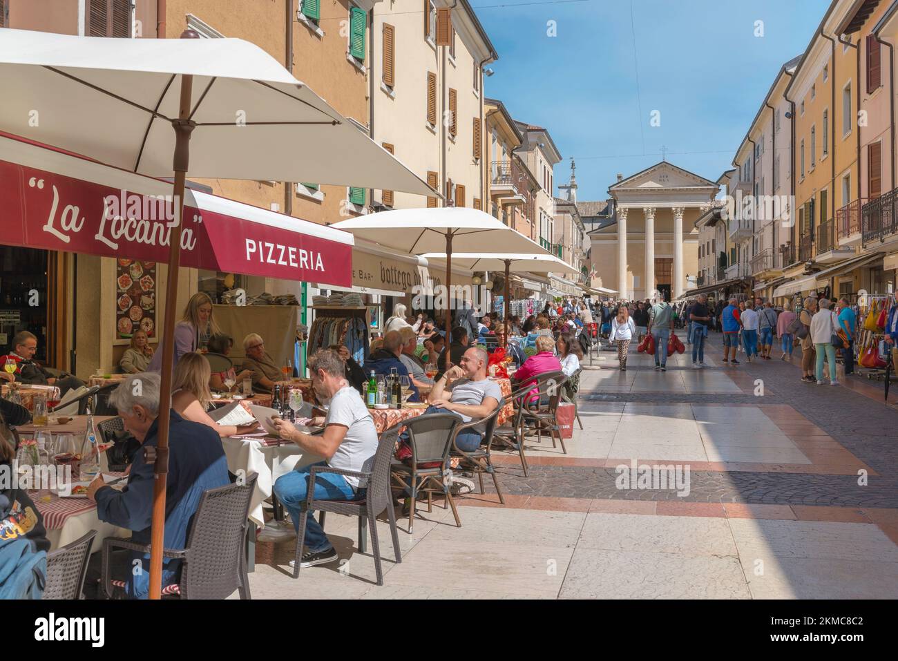 Bardolino town Italy, view in summer of people relaxing at cafe tables in Via San Martino in the historic old town center of Bardolino, Lake Garda Stock Photo