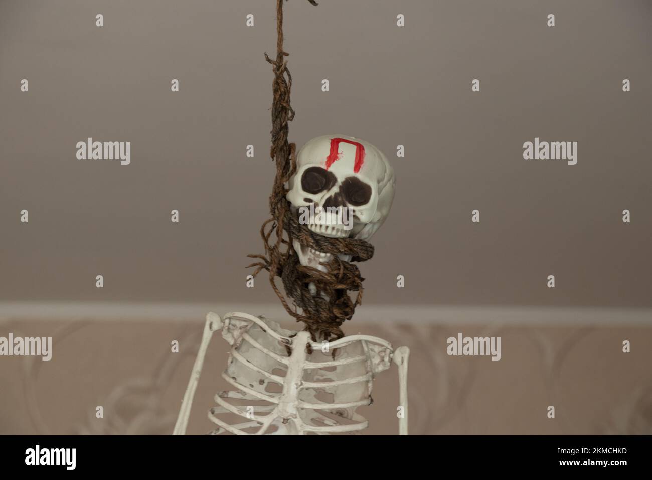 A plastic skeleton hangs on a rope on a chandelier at home in Ukraine with the letter p on the forehead, stop war, stop terror, war Stock Photo