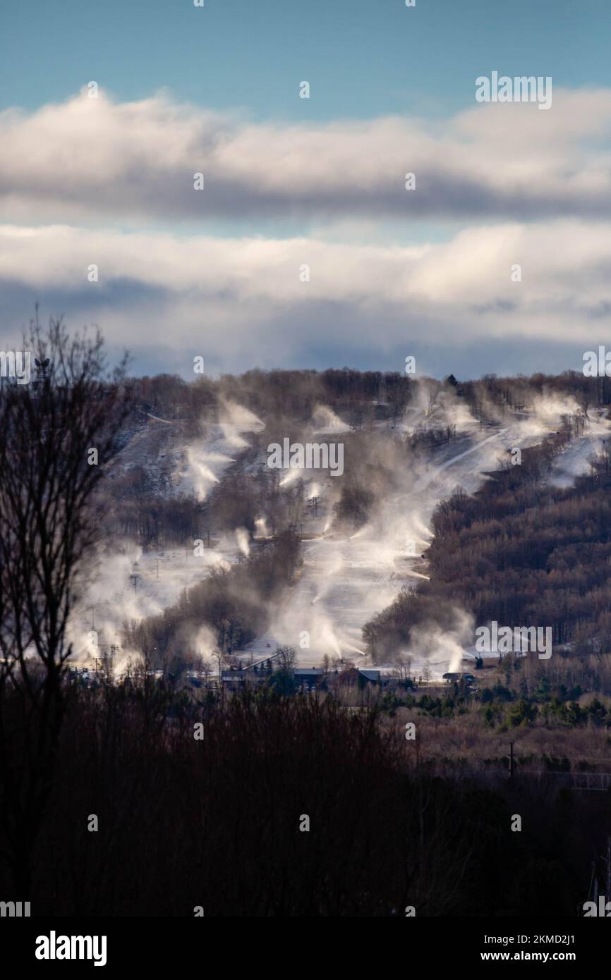 Snow cannons making snow on Granite Peak Ski Hill in Rib Mountain, Wausau, Wisconsin just before they open, vertical Stock Photo