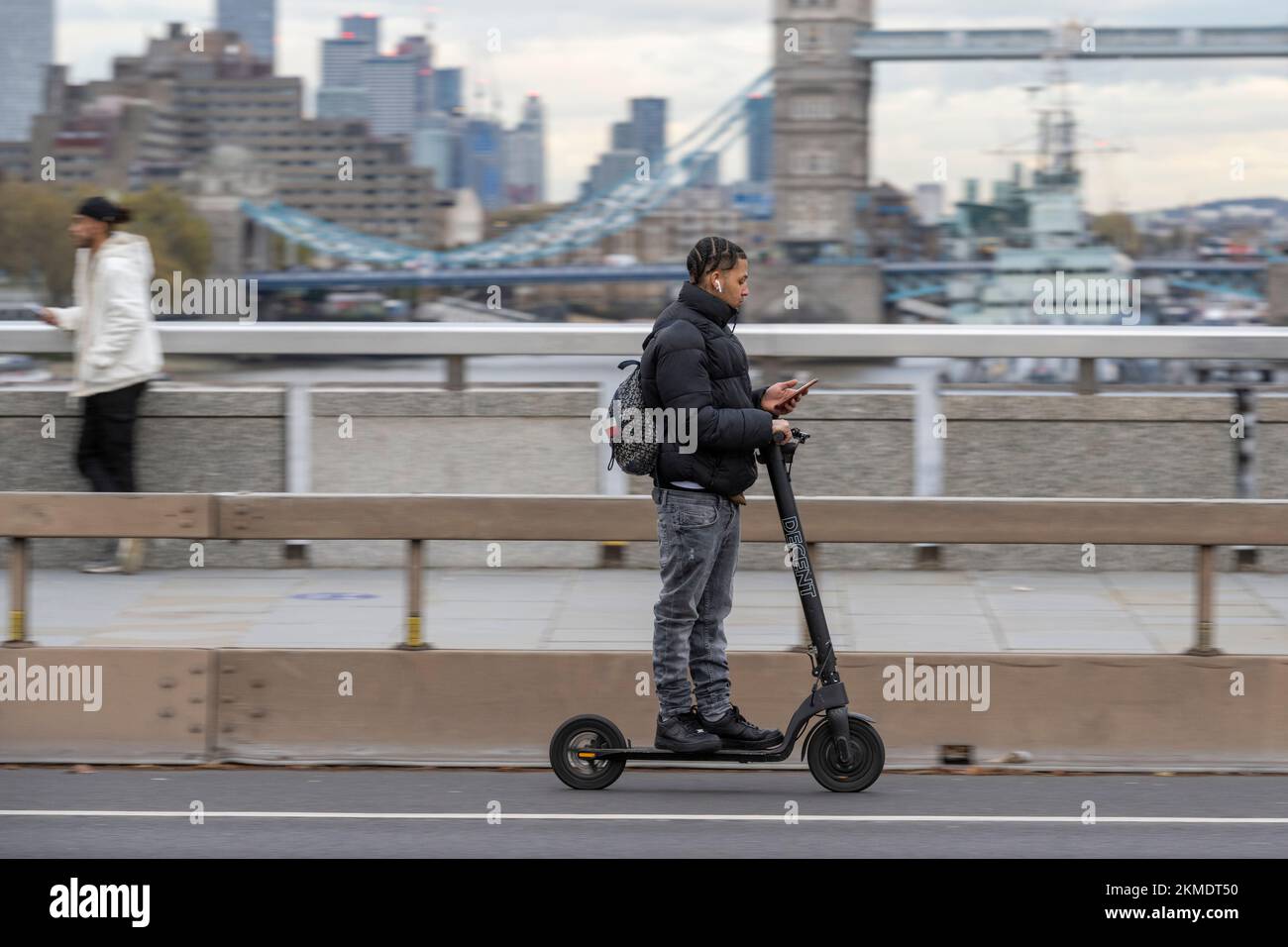 A man riding an escooter along London Bridge. Riding a privately owned