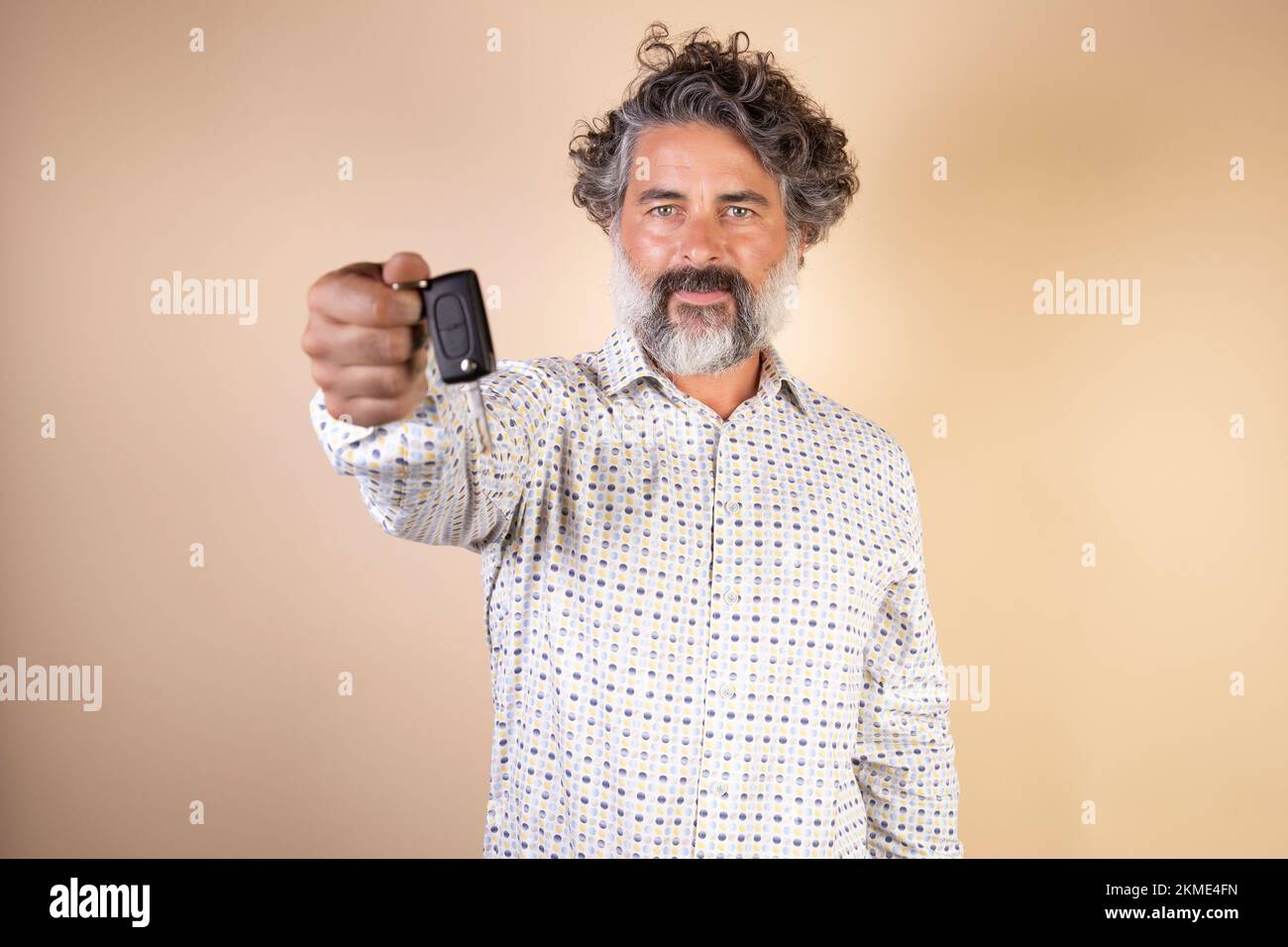 A middle-aged Caucasian bearded man holding a car key isolated on a ...
