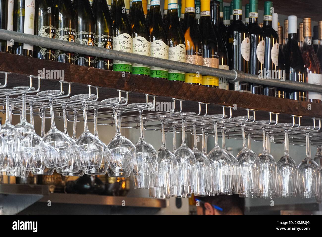 Wine bottles on the wooden shelf and wine glasses on a rack in restaurant, London England United Kingdom UK Stock Photo