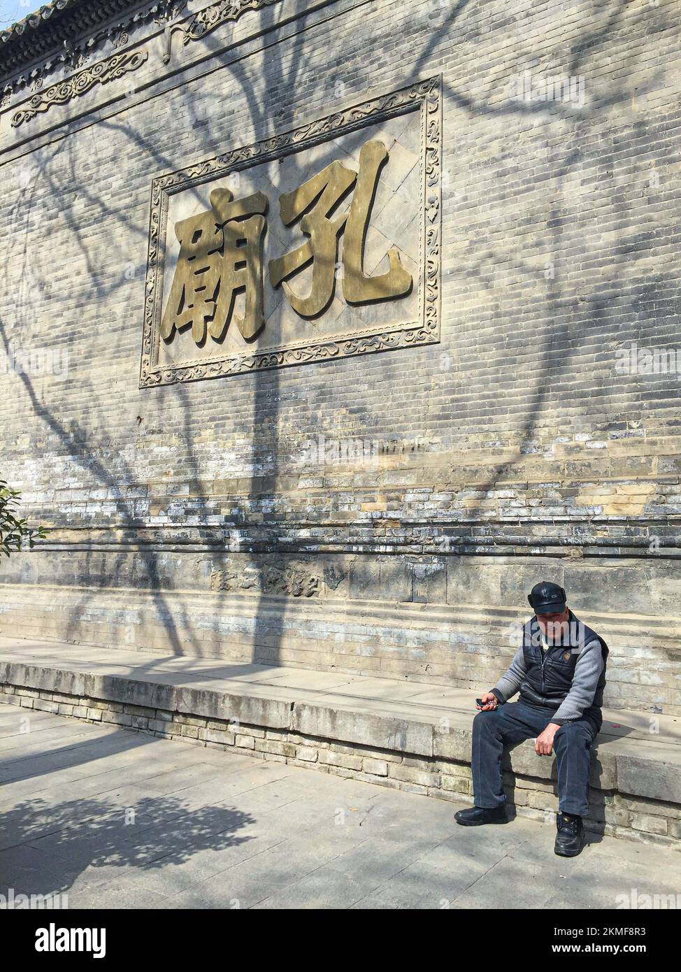 An old man sitting in front of the Confucian Temple 'Kong Miao' in Xi'an City, China Stock Photo