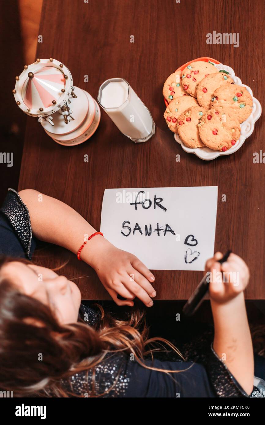 Top view of a little girl leaving cookies and glass of milk for Santa
