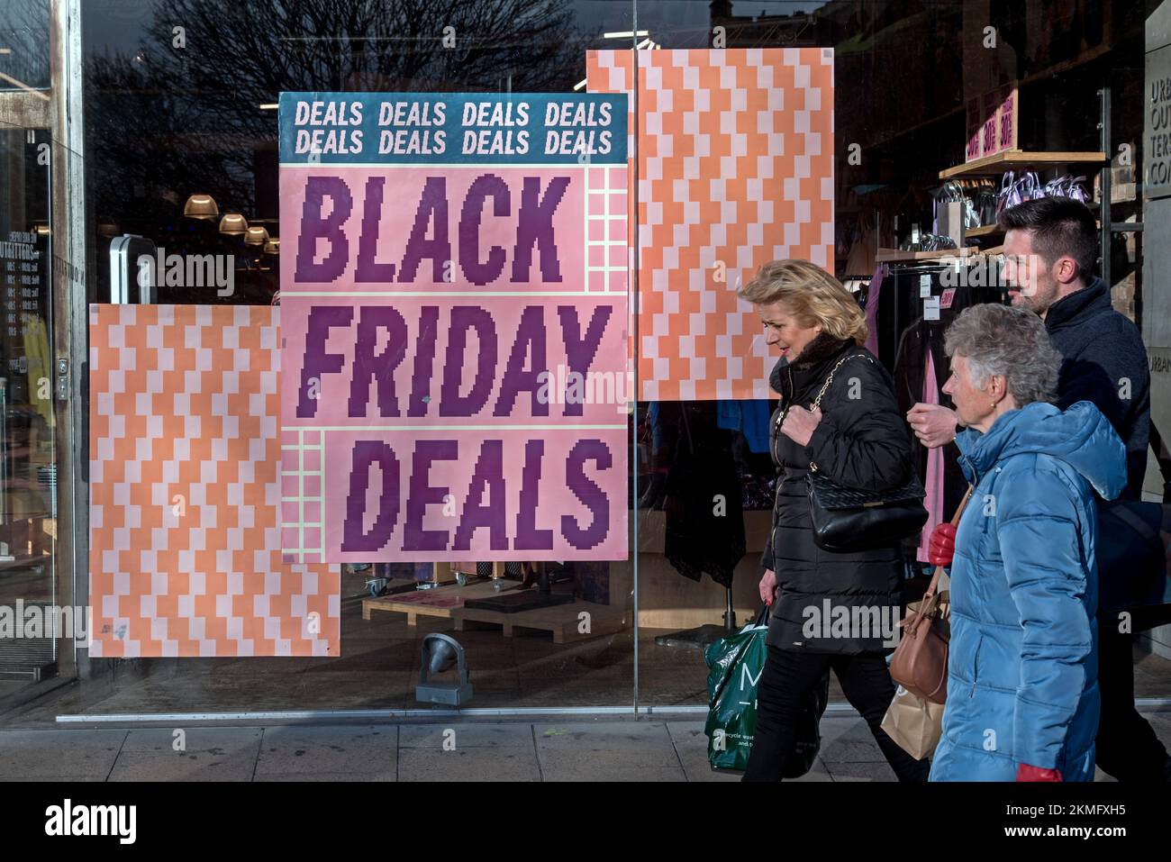 people walking by Black Friday posters in the window of Urban Outfitters on Princes Street, Edinburgh, Scotland, UK. Stock Photo