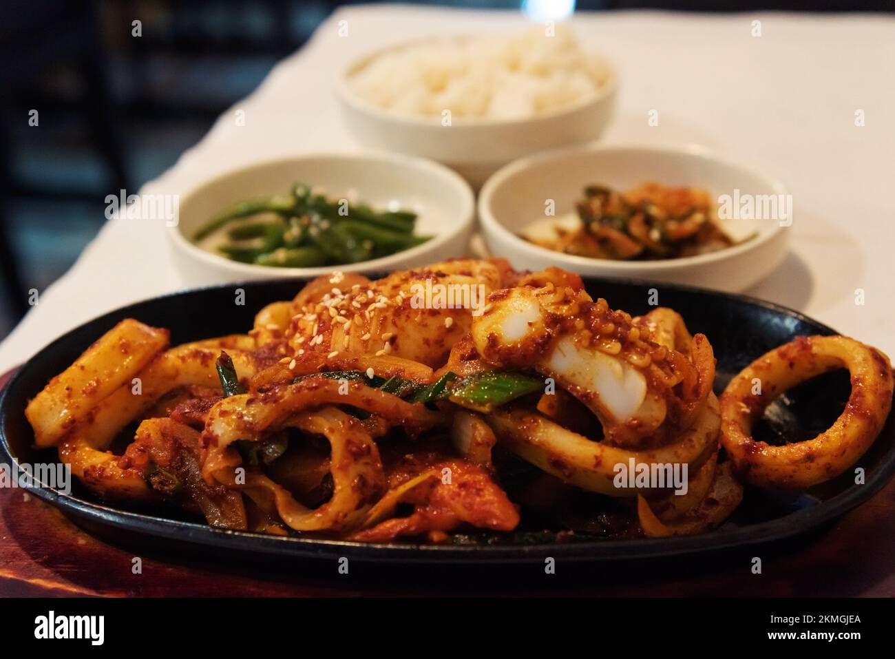 Stir fried squid, rice, kimchi and vegetables as side dishes in