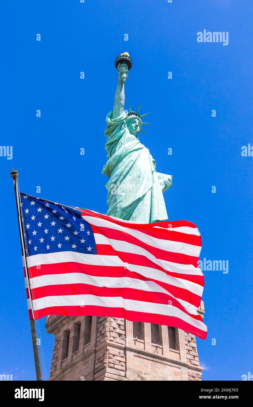 American flag waving in the wind against Statue of Liberty Stock Photo
