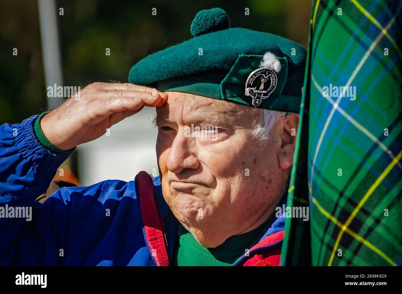 A man salutes as he holds a tartan representing the Henderson clan during the parade of clan tartans at the Scottish Highland Games in Gulfport, Miss. Stock Photo