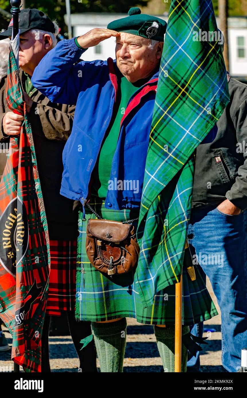 A man salutes as he holds a tartan representing the Henderson clan during the parade of clan tartans at the Scottish Highland Games in Gulfport, Miss. Stock Photo
