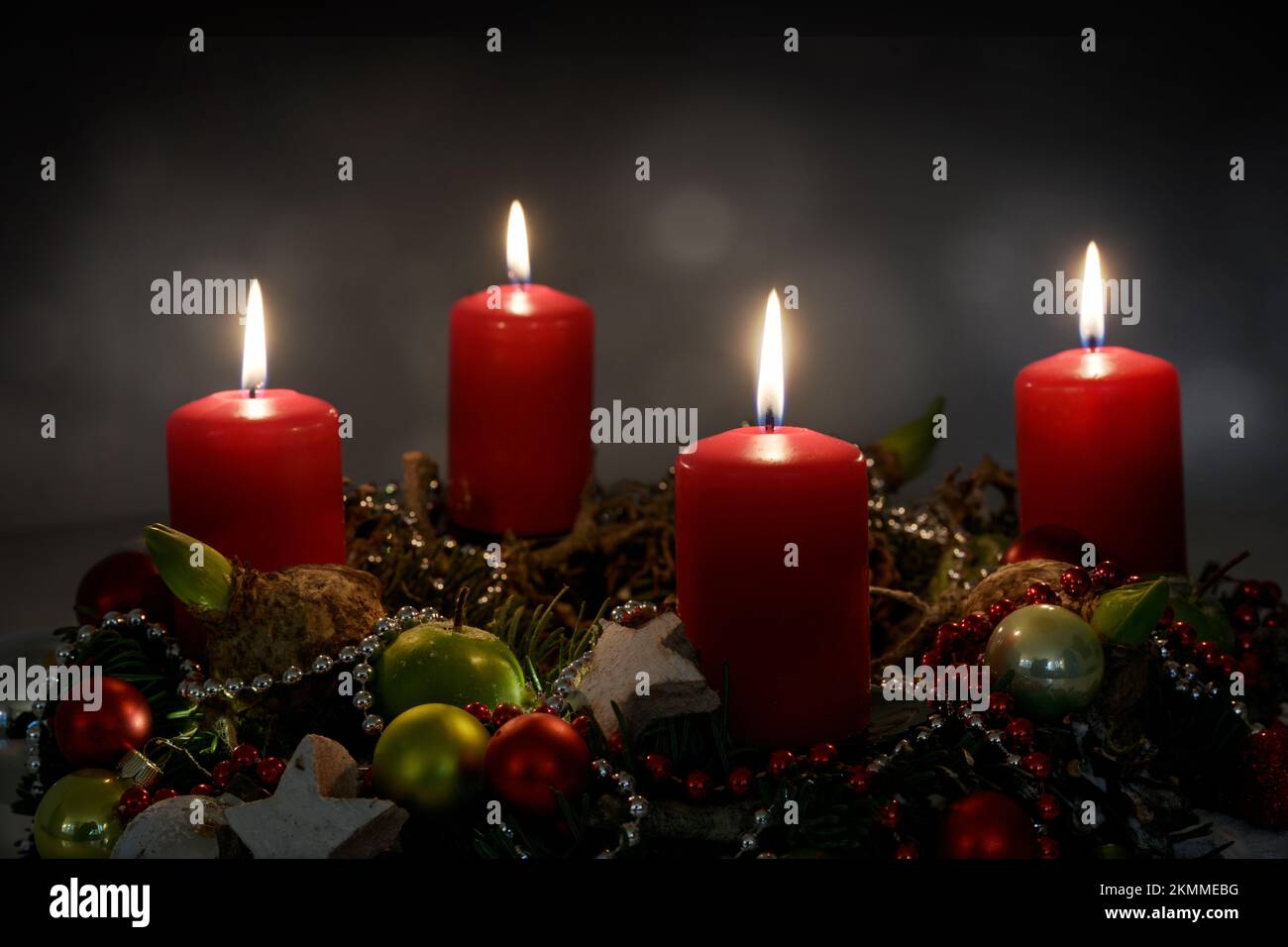Candle light in the night, part of an Advent wreath with four red candles and Christmas decoration against a dark background, copy space, selected foc Stock Photo