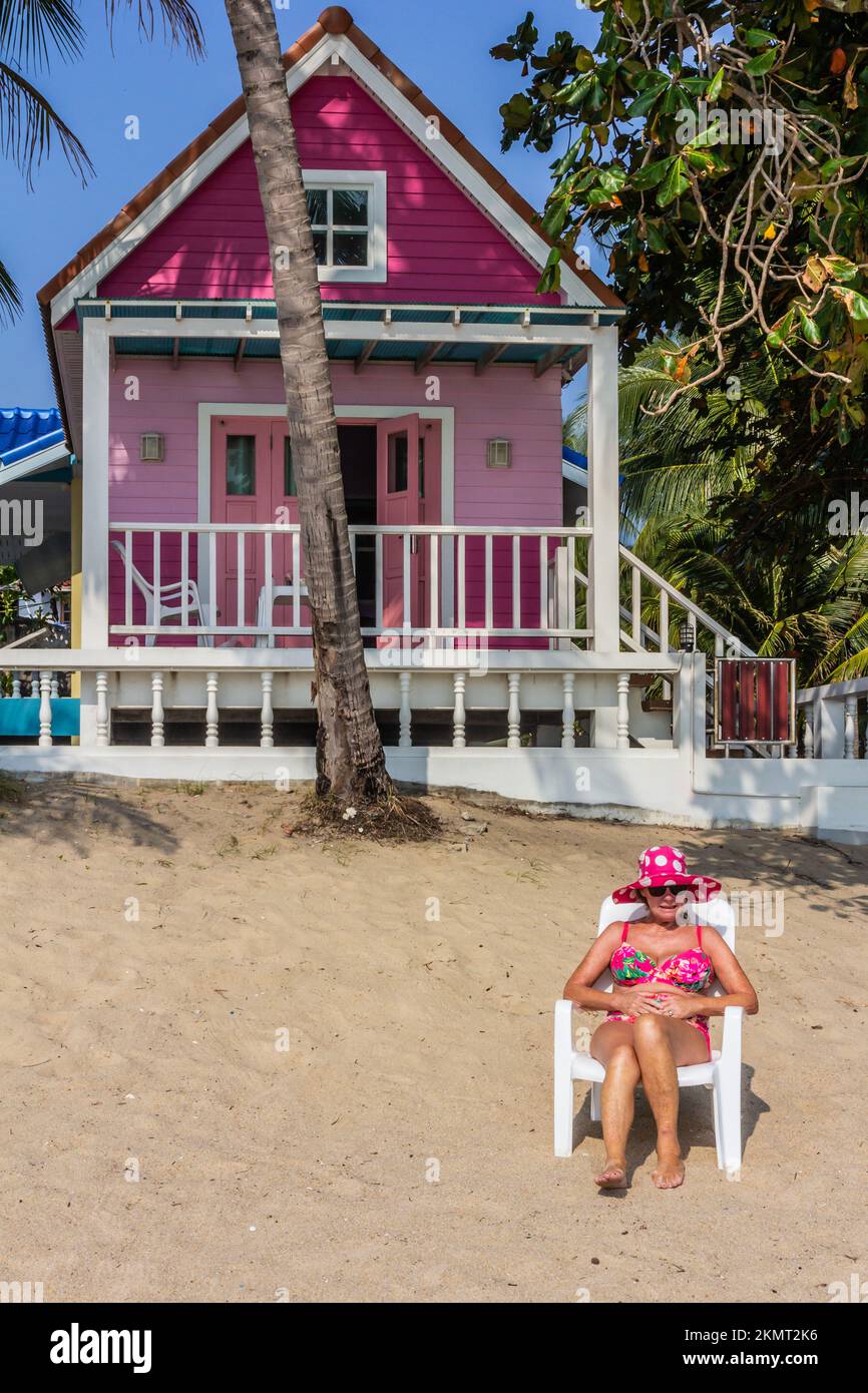 Woman in pink hat and bikini on the neach outside a pink Bungalow, Nakhon Si Thammarat, Thailand Stock Photo