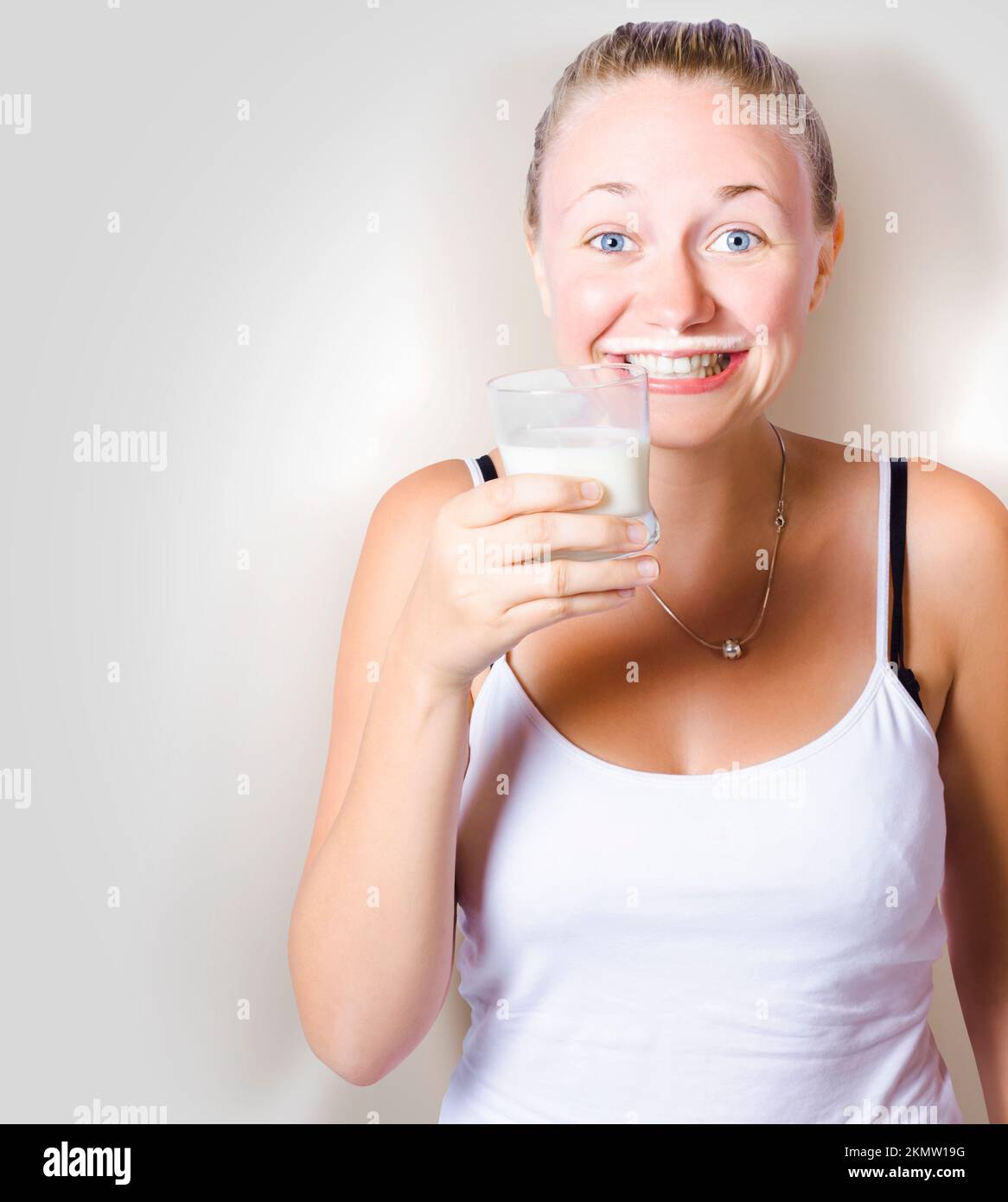 Funny woman smiling while enjoying a glass of full cream milk with