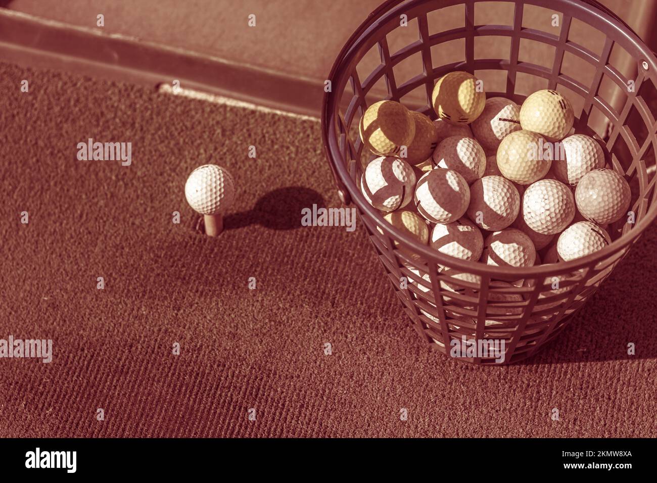 Old toned image of a bucket of golf balls next to practise tee a