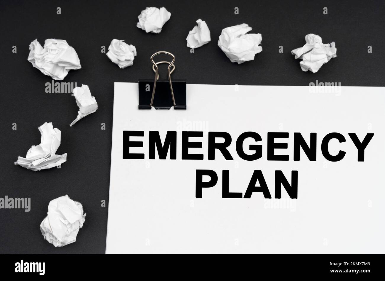 Industrial concept. On a black background, there are crumpled pieces of paper and paper with the inscription - Emergency Plan Stock Photo