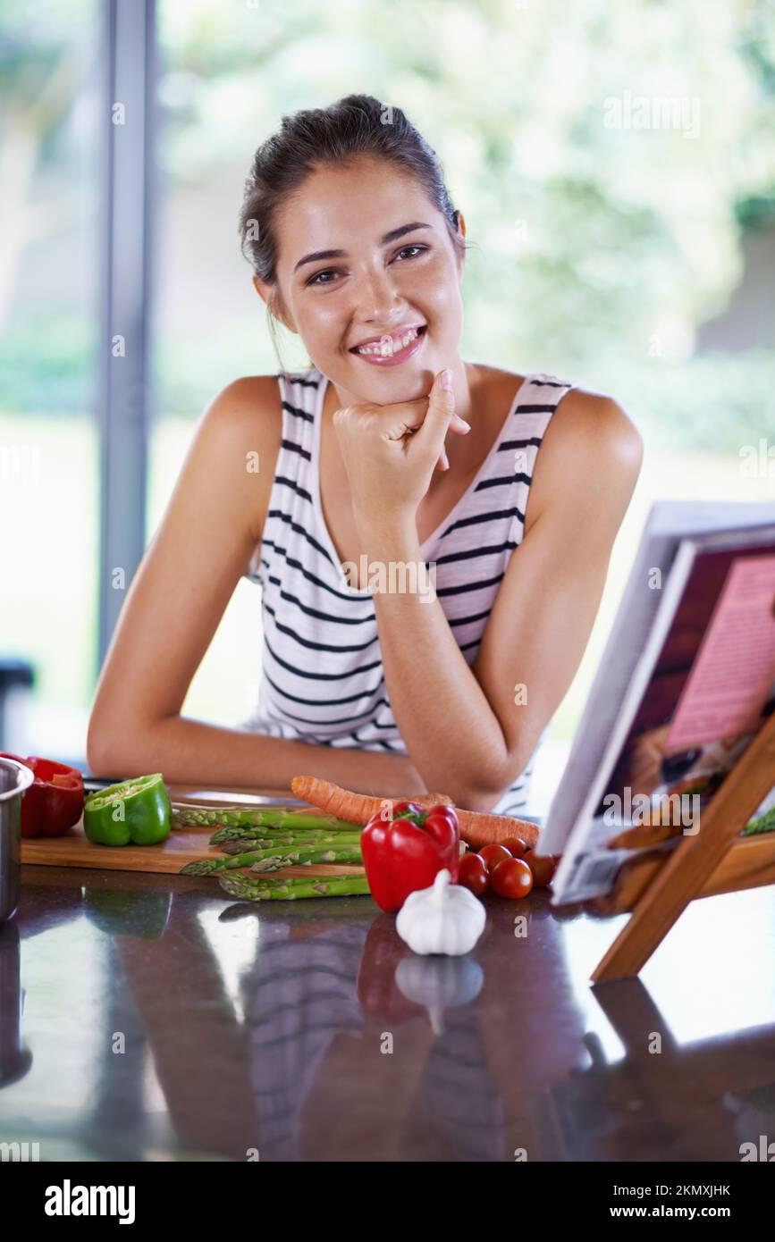 Living the healthy way. A young woman cooking from a recipe book. Stock Photo