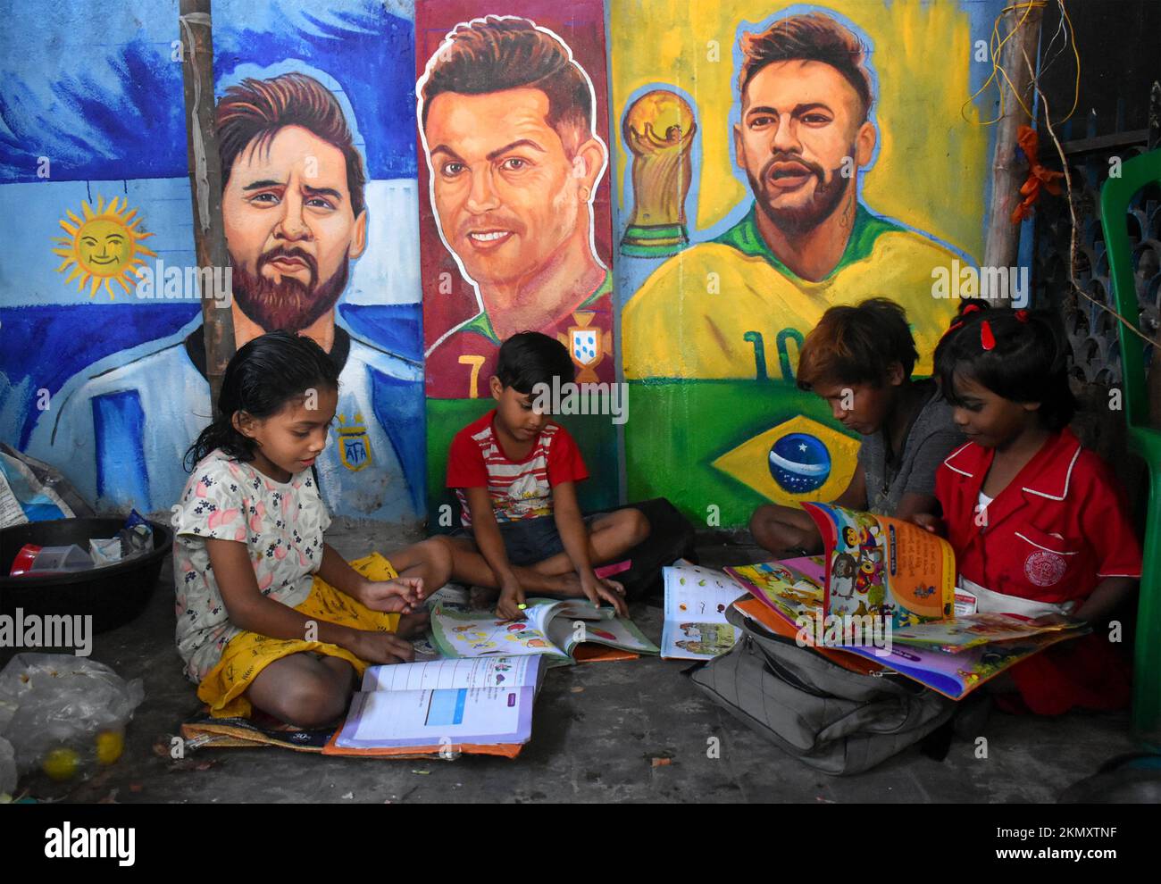 Kolkata, West Bengal, India. 26th Nov, 2022. A Group of children is reading in front of the images of Lionel Messi, Cristiano Ronaldo, and Neymar Junior on a roadside footpath during the FIFA World cup 2022 in Kolkata. (Credit Image: © Sudipta Das/Pacific Press via ZUMA Press Wire) Stock Photo