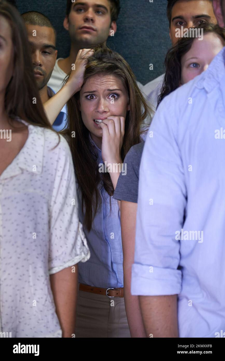 I have to get out of here. a fearful young woman feeling trapped by the crowd. Stock Photo