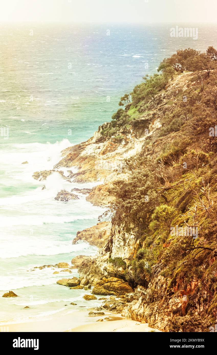 Retro rocky coastline cliff with colorful rays of sunlight and tropical