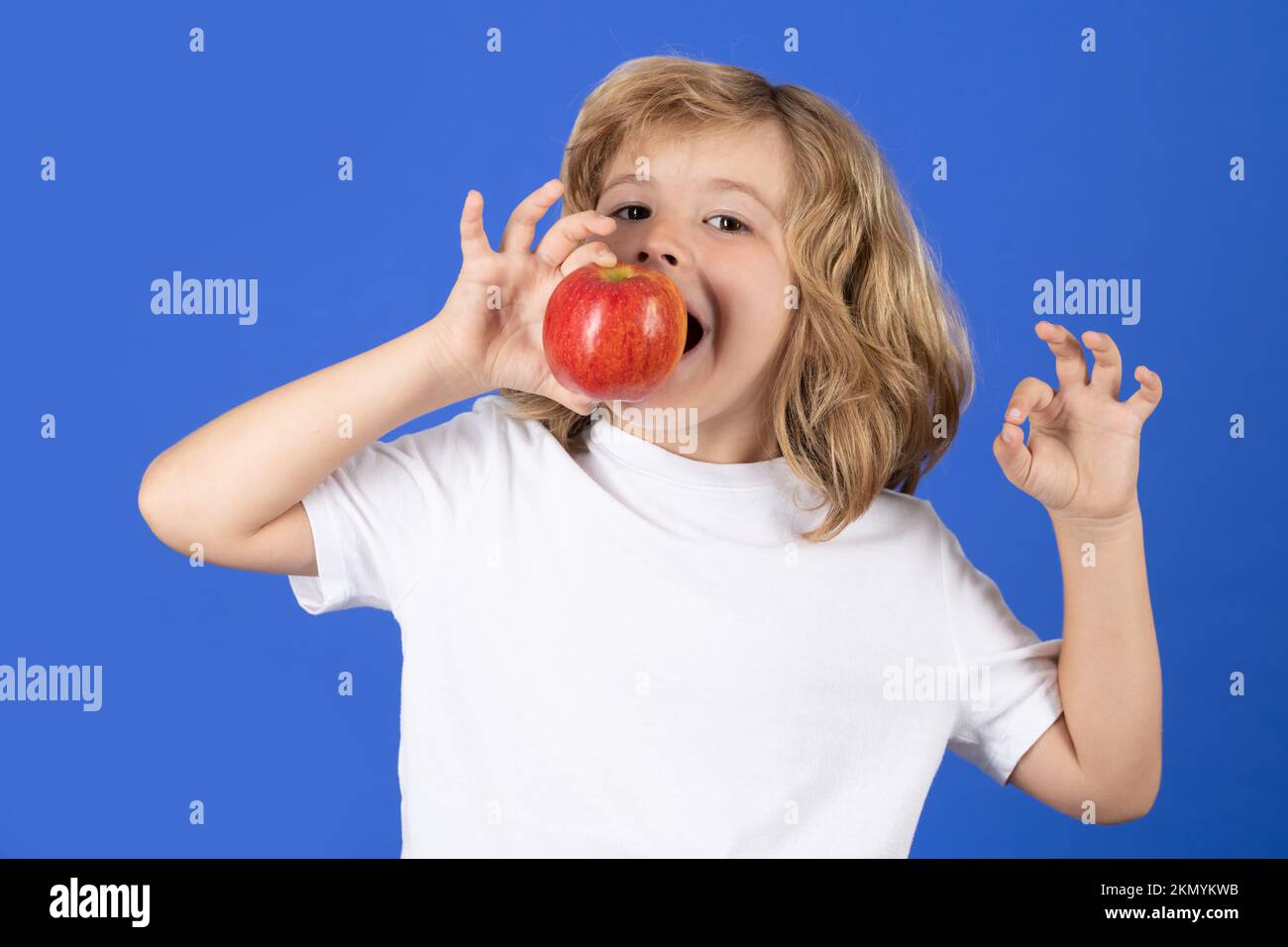 Child biting apple on studio isolated background Stock Photo Alamy