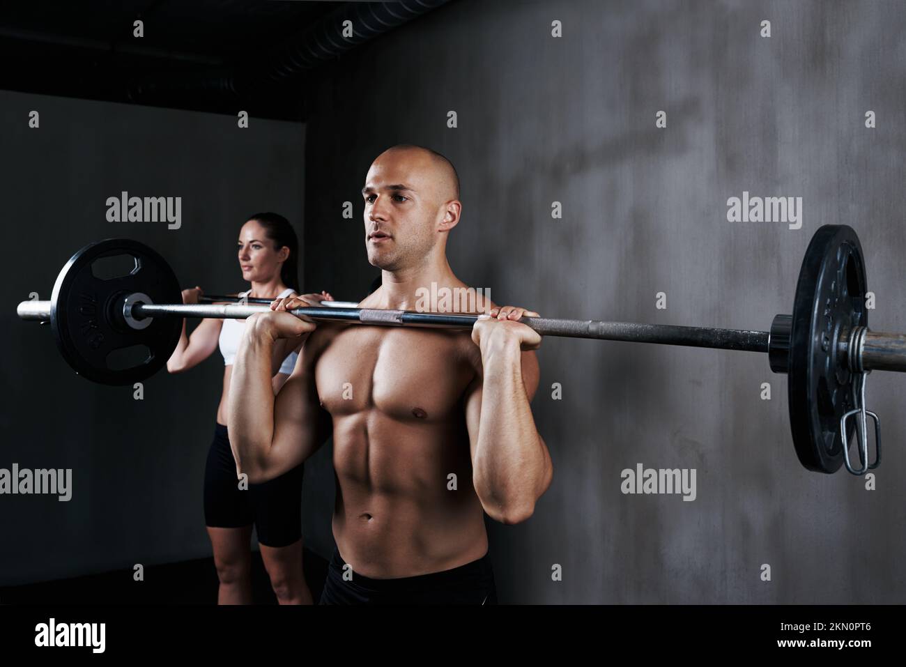 Training to fighting fit. two people lifting barbells during a