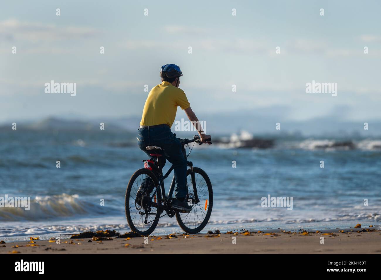 A cyclist in yellow Tshirt riding on the beach Stock Photo Alamy