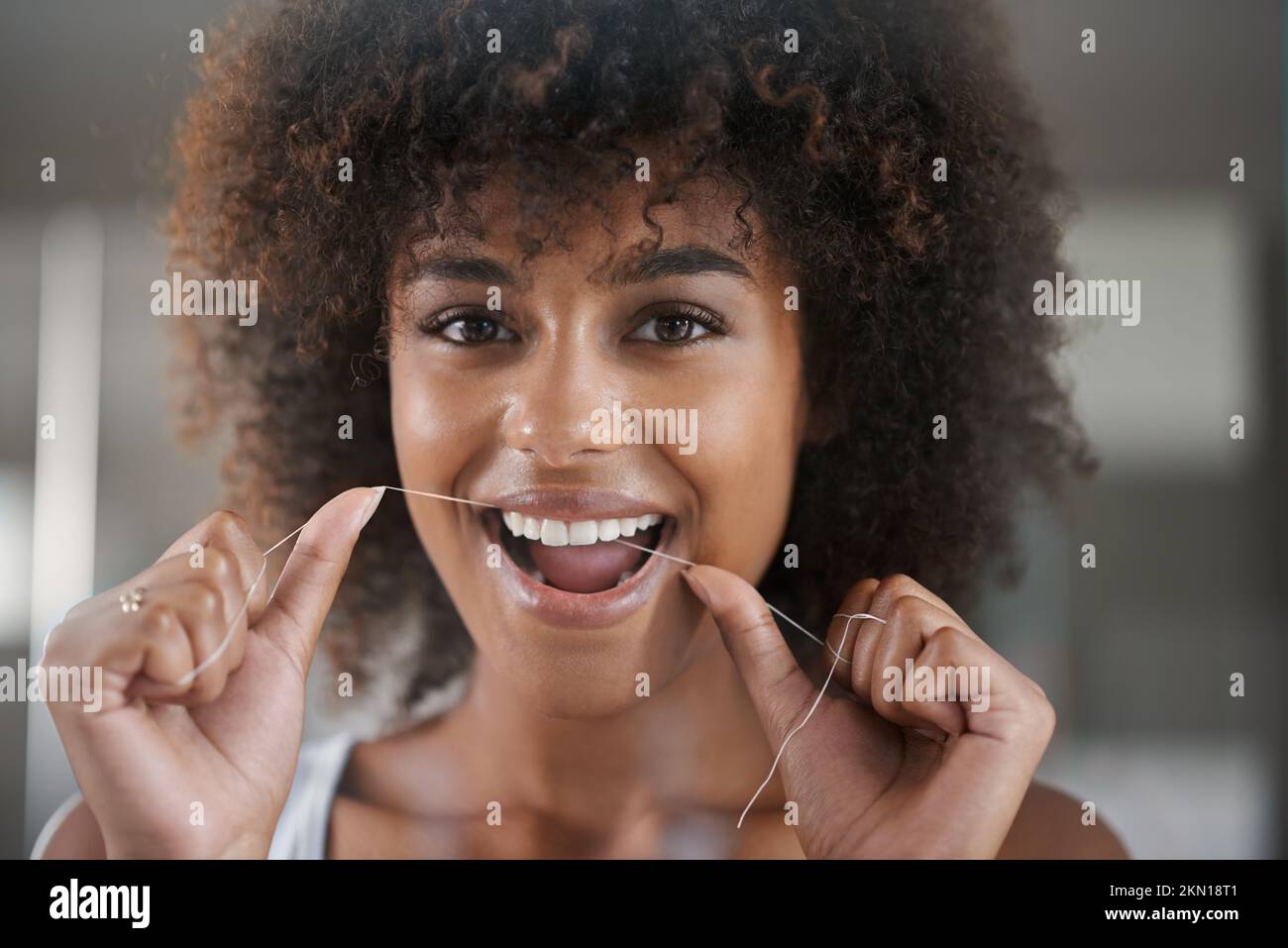 Creating the perfect smile. a young woman flossing her teeth in the
