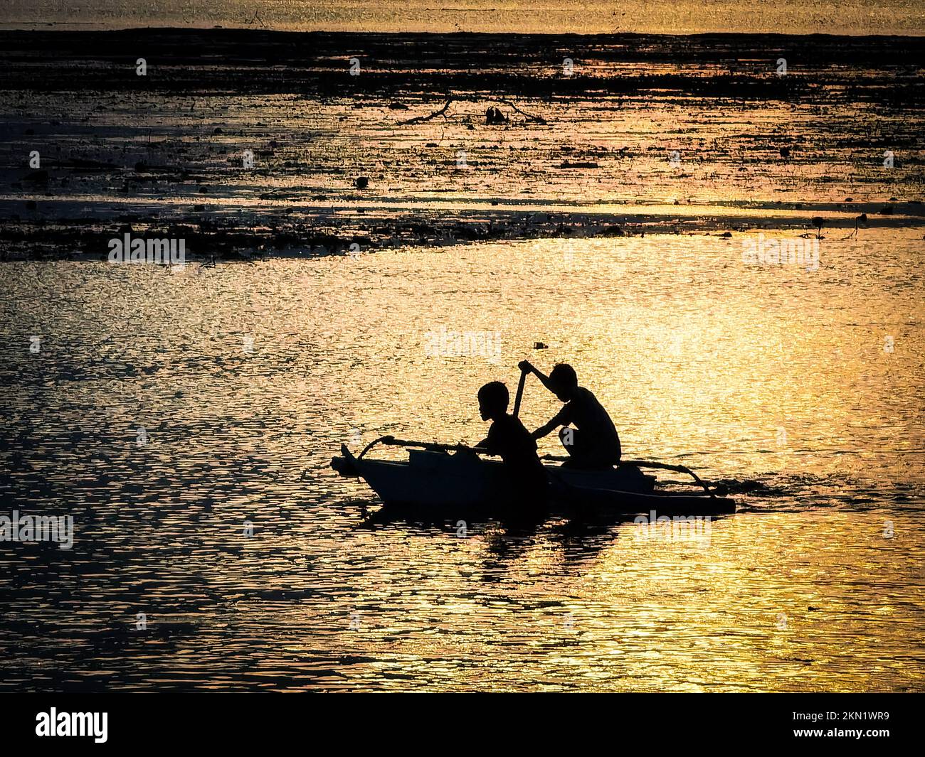 A silhouette fishermen on a fishing boat at sunset in manual in the ...