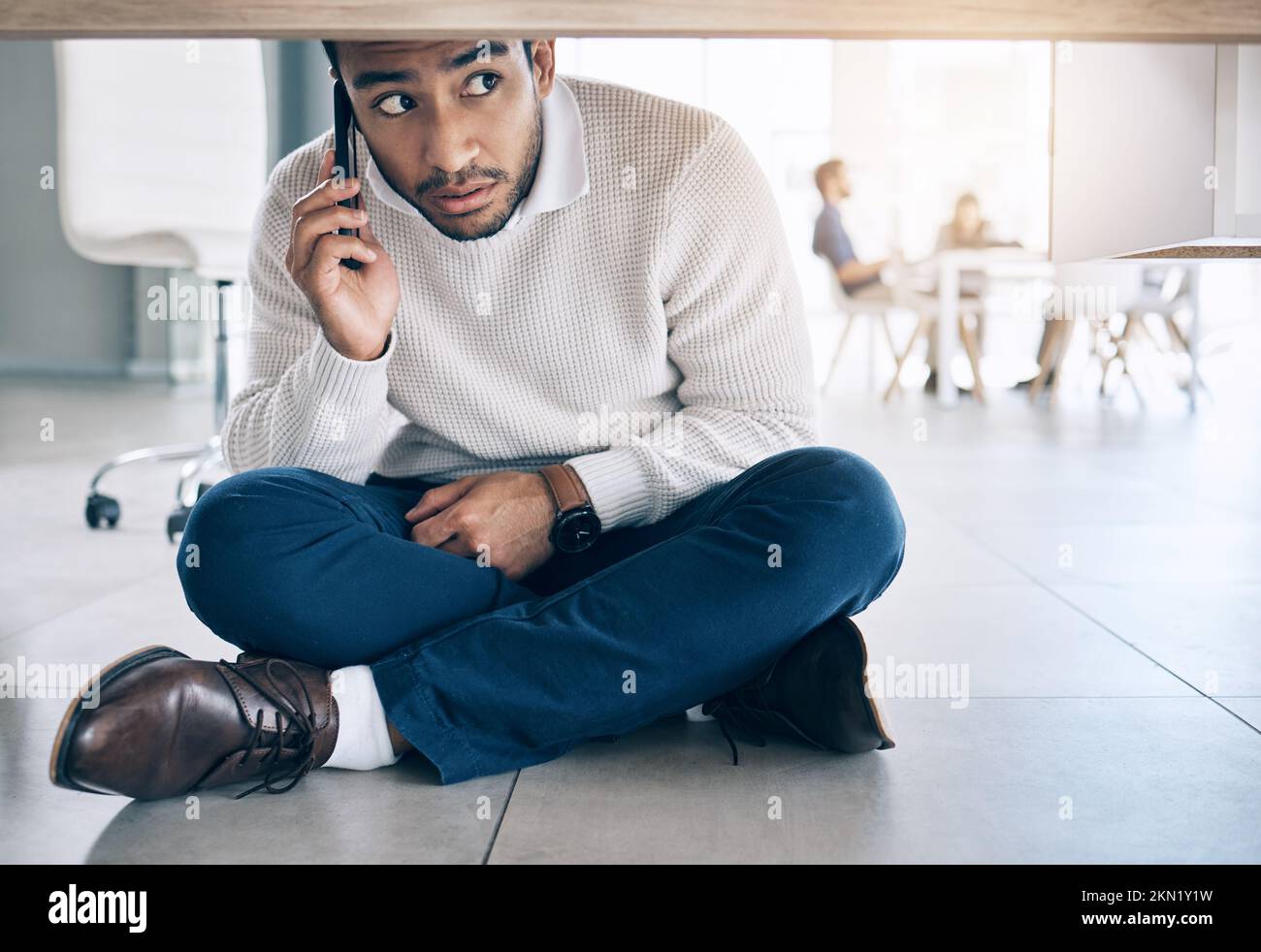 Phone call, office and businessman sitting on floor under table with