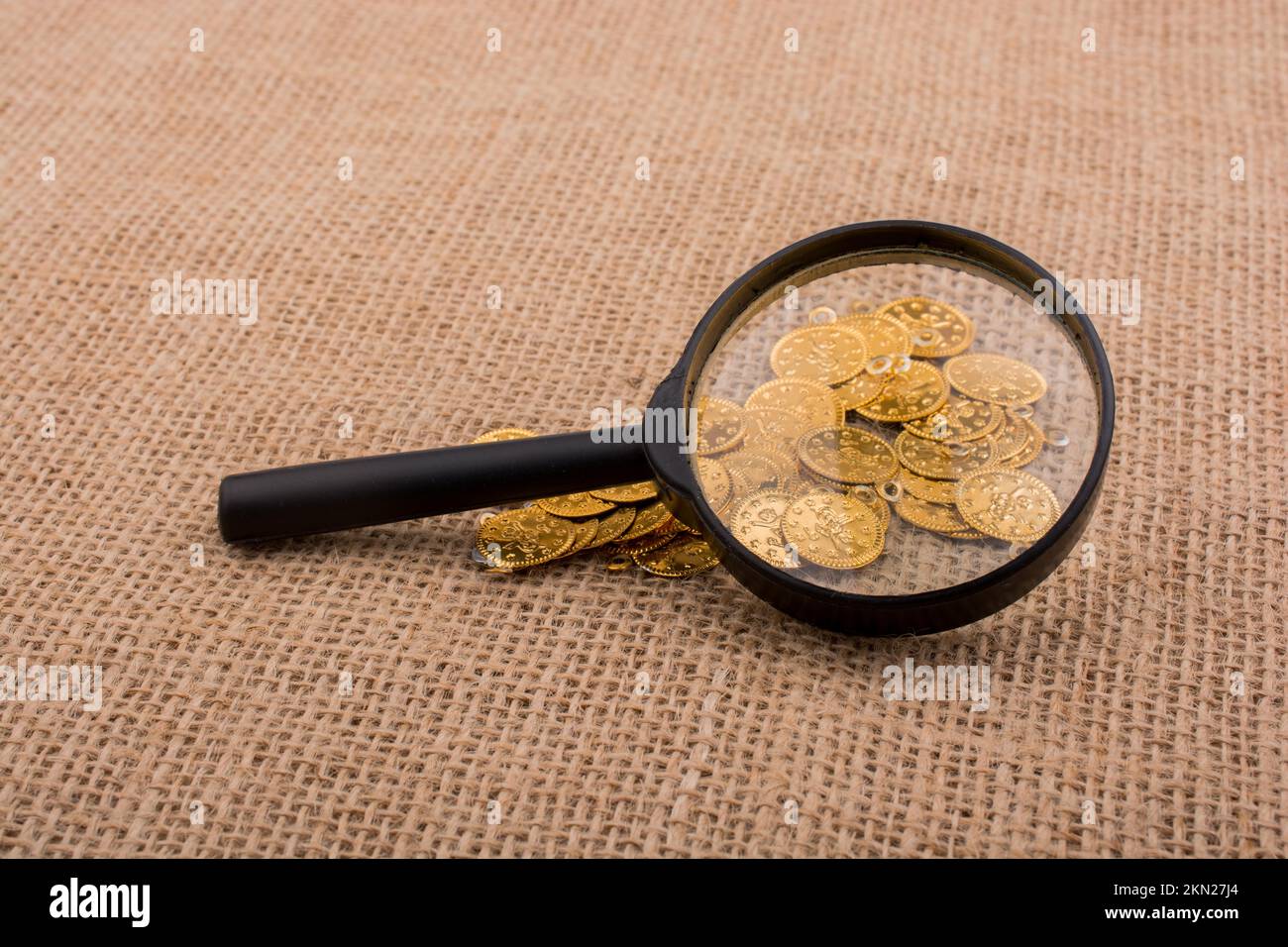 Plenty of fake gold coins behind magnifying glass Stock Photo Alamy