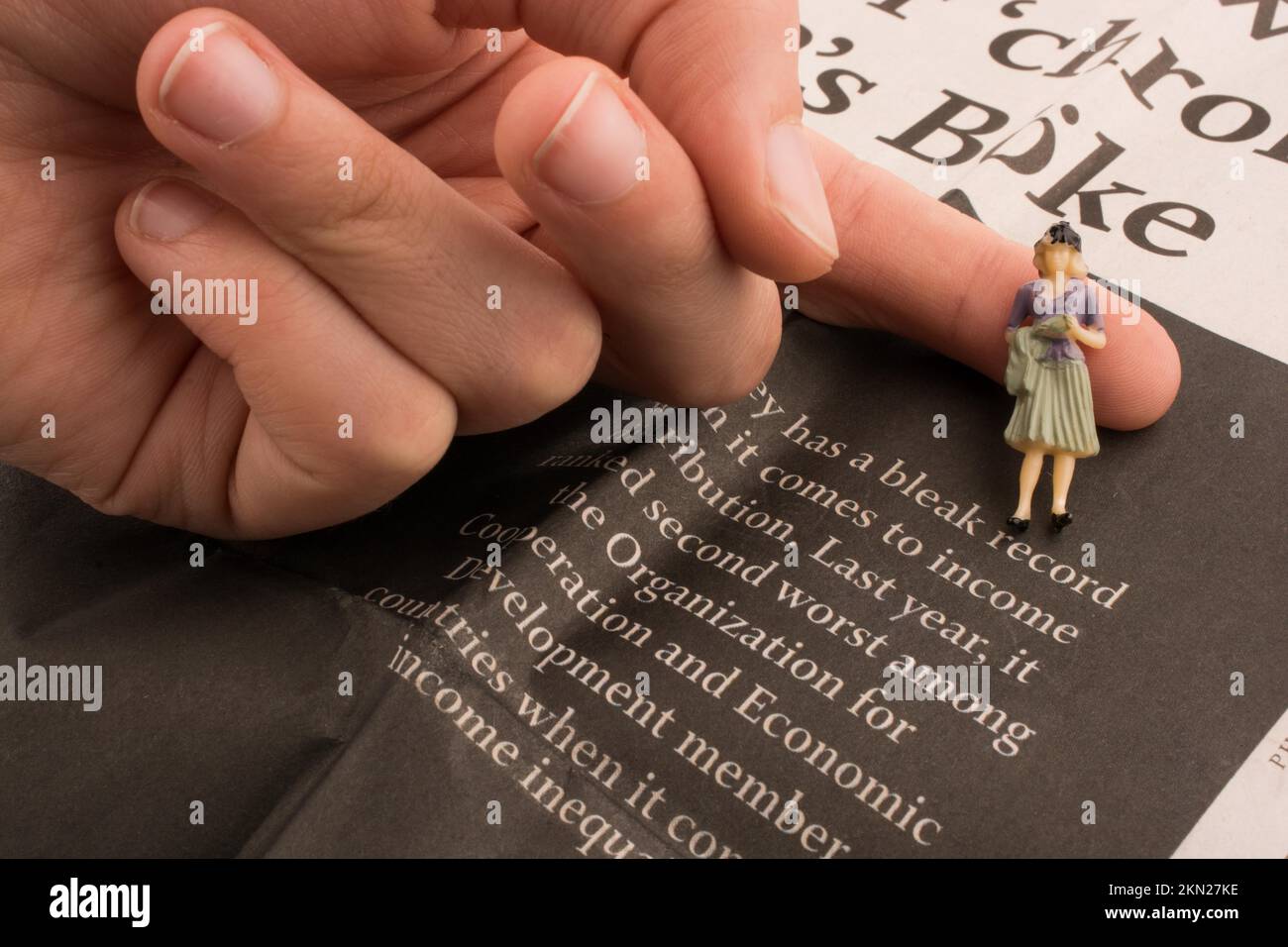 Hand holding a human figure on a newspaper Stock Photo