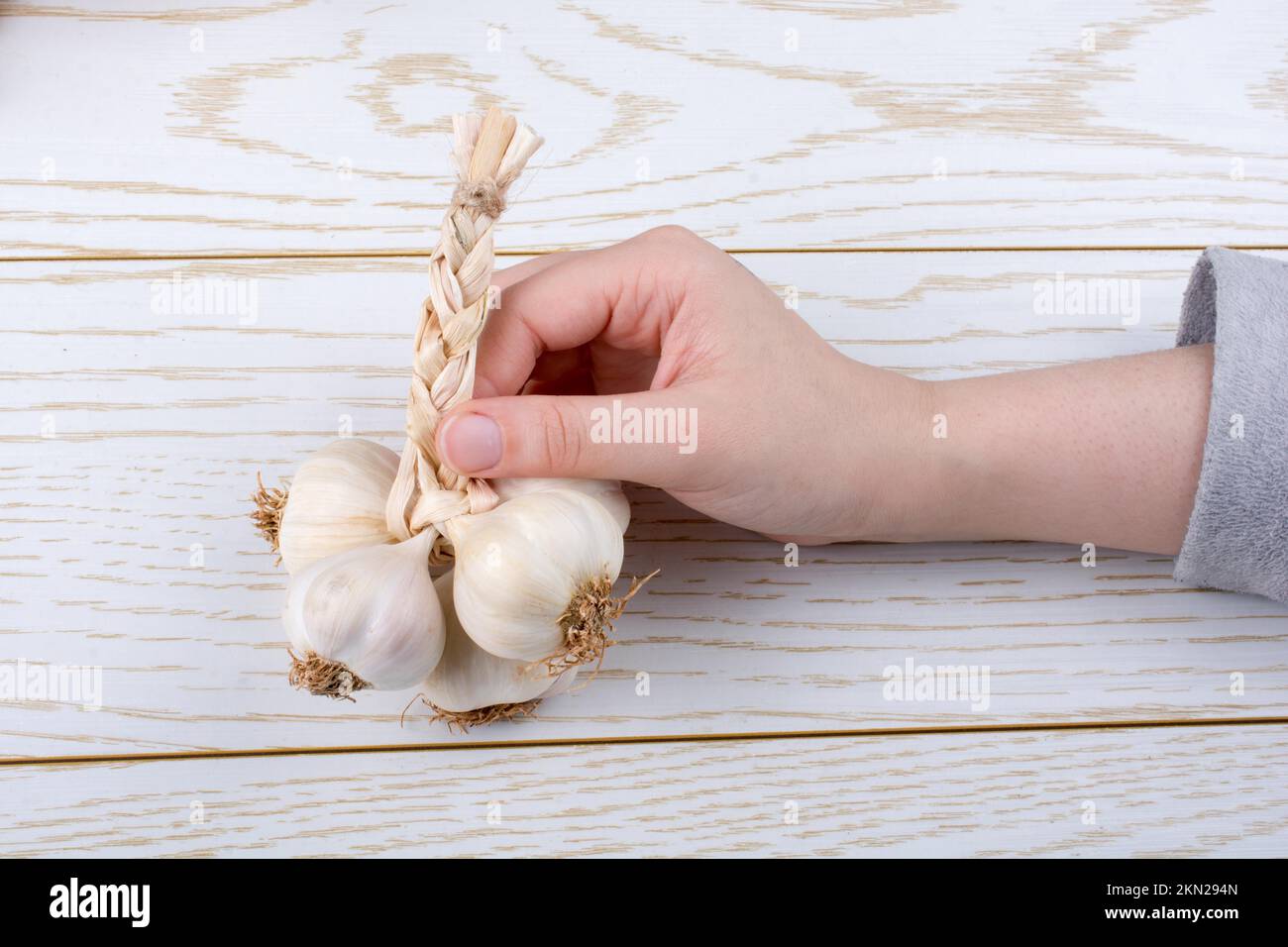 Hand holding cloves of garlic on a wooden texture Stock Photo - Alamy