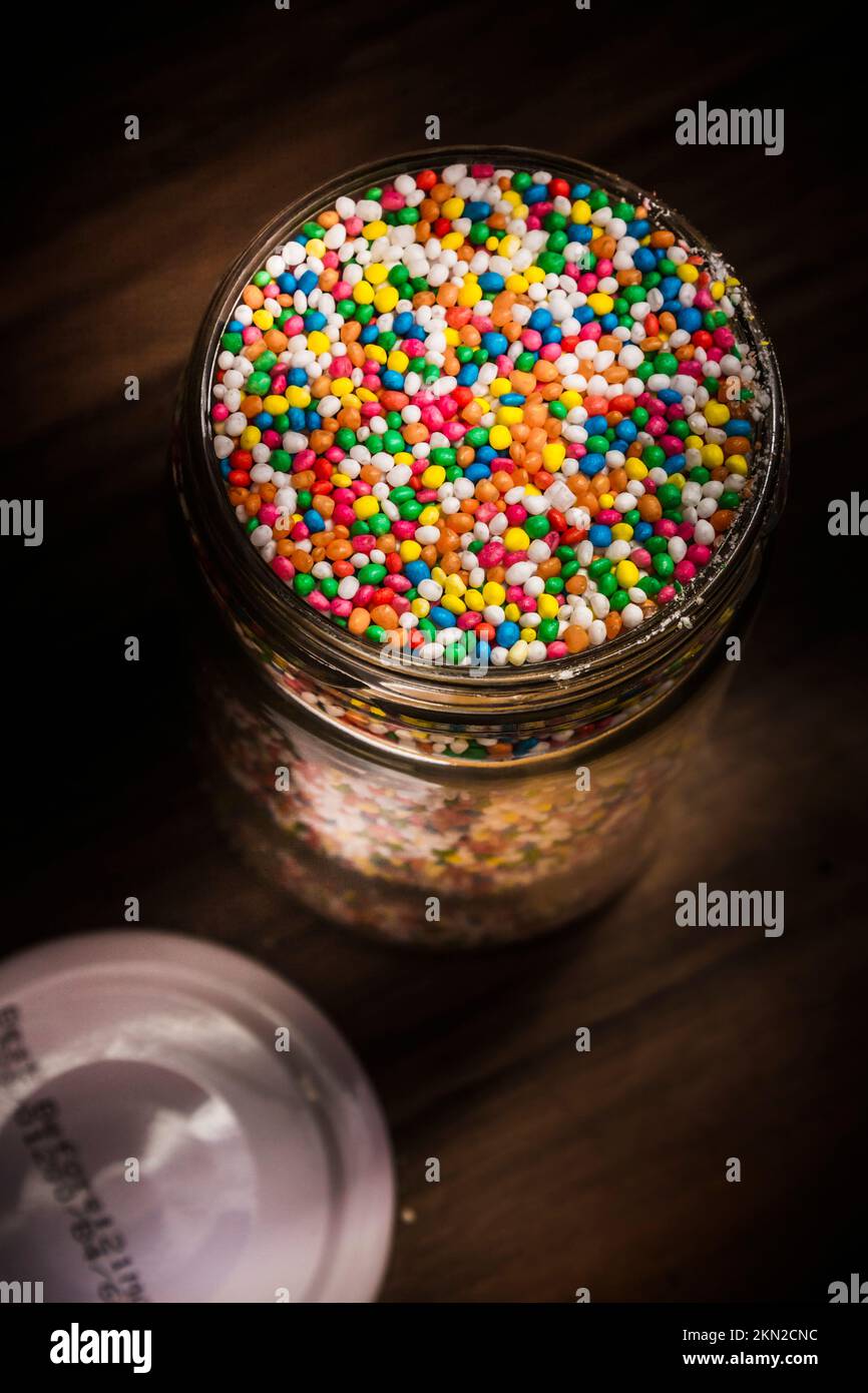 Food photography on colourful sugar pearls festive ingredients in open glass jar. Icing decorations Stock Photo