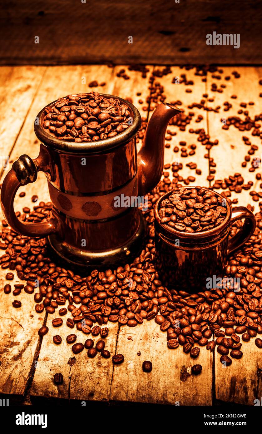 Ceramic coffee pot and mug overflowing with beans for concept about its