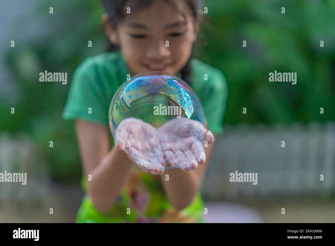 A young girl making bubbles in a garden. Stock Photo