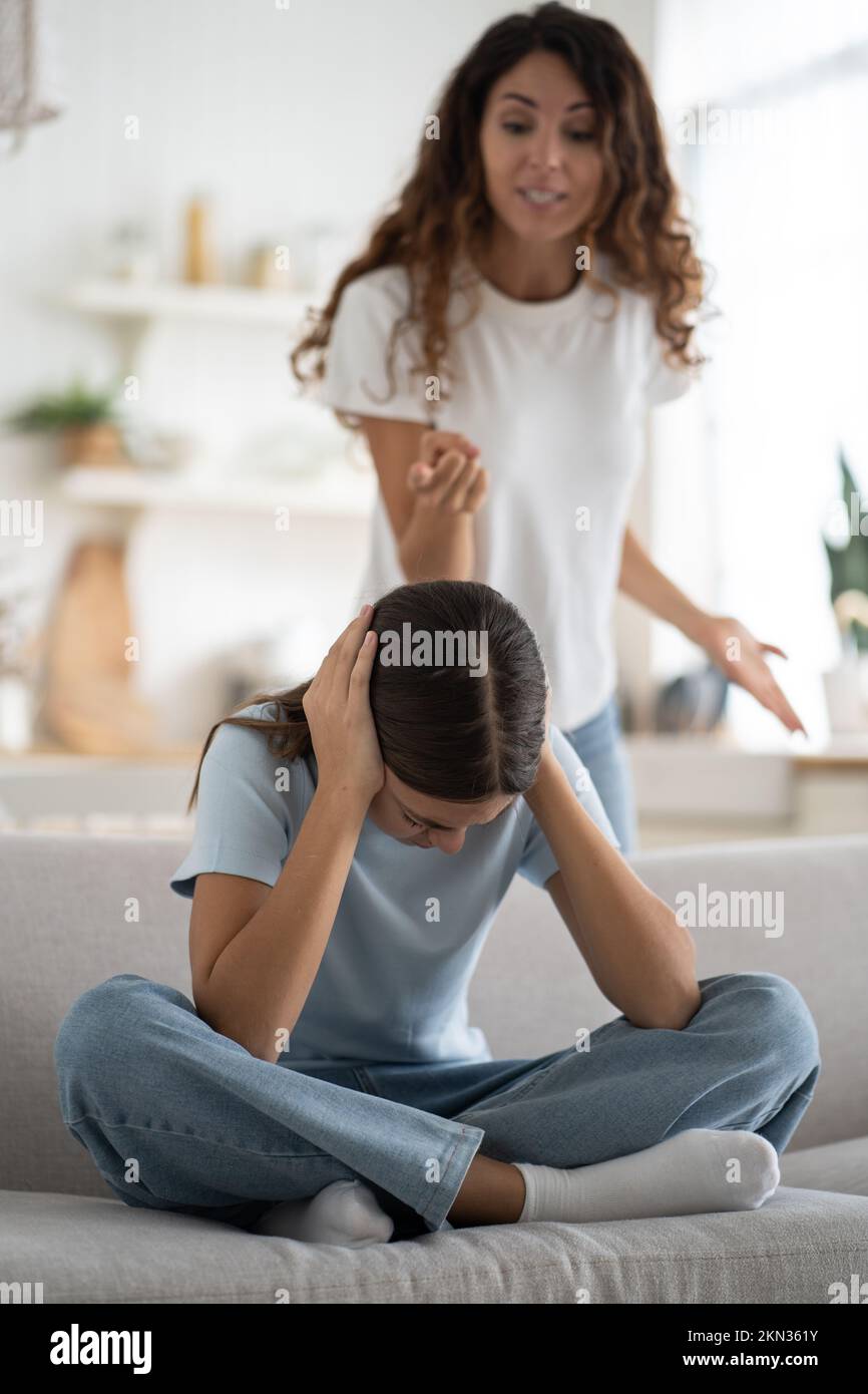 Depressed teen girl covering ears not to listen angry furious mother