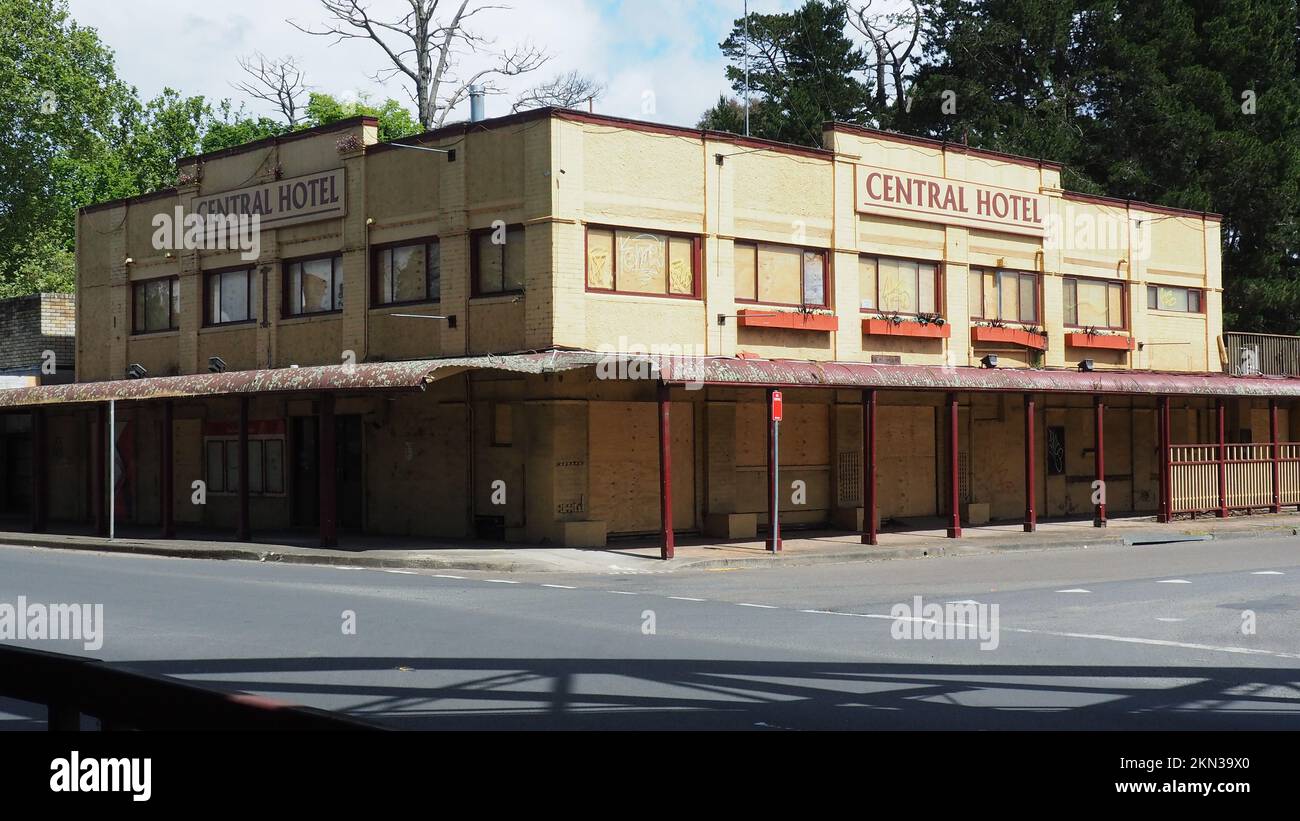 The boarded up and rundown Central Hotel (est. 1878)  in Moss Vale NSW. Railway over bridge shadow on the intersection. Stock Photo