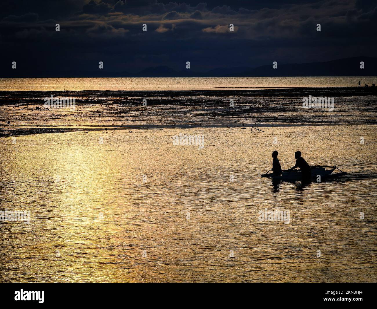 A beautiful scene of a silhouette fishermen on a fishing boat at sunset ...