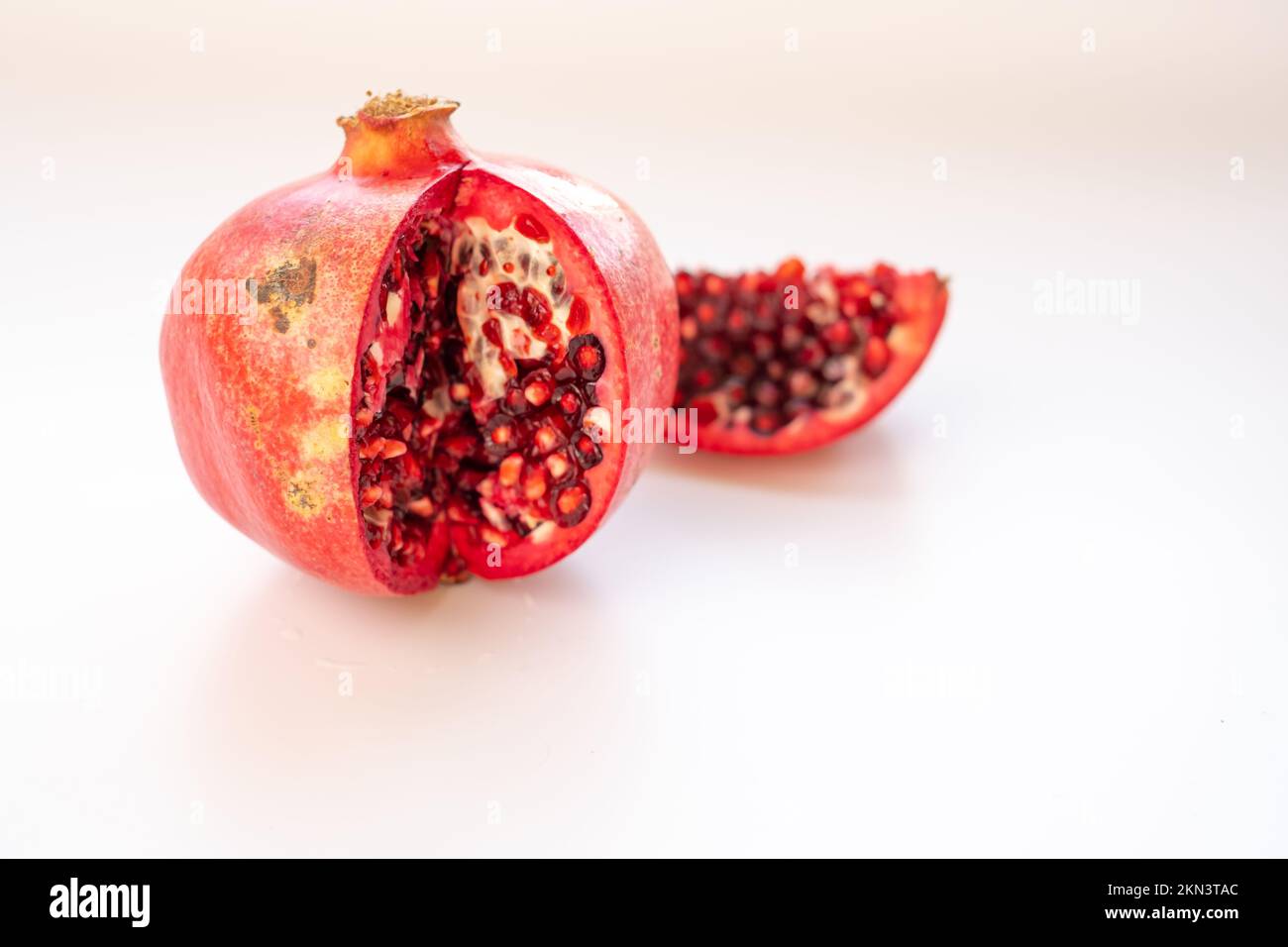white background, dirty hormone free red pomegranate. isolated ,old style natural sliced pomegranate Stock Photo