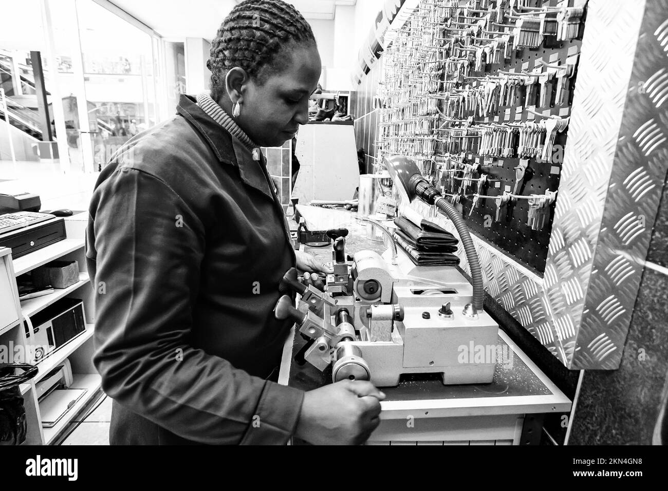 A grayscale shot of a woman using a machine in a shoe repair and dry