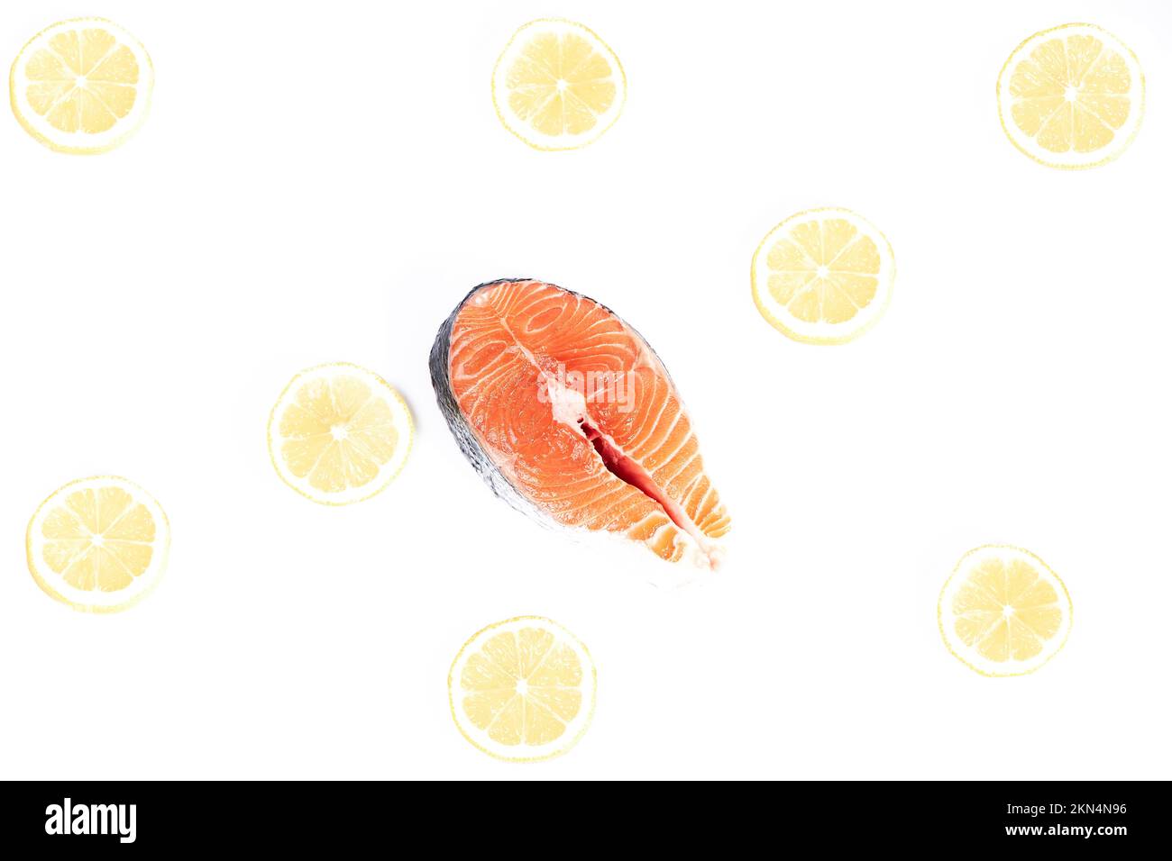 Salmon, slice of fresh raw fish together with lemon slices, isolated on white background. Healthy food Stock Photo
