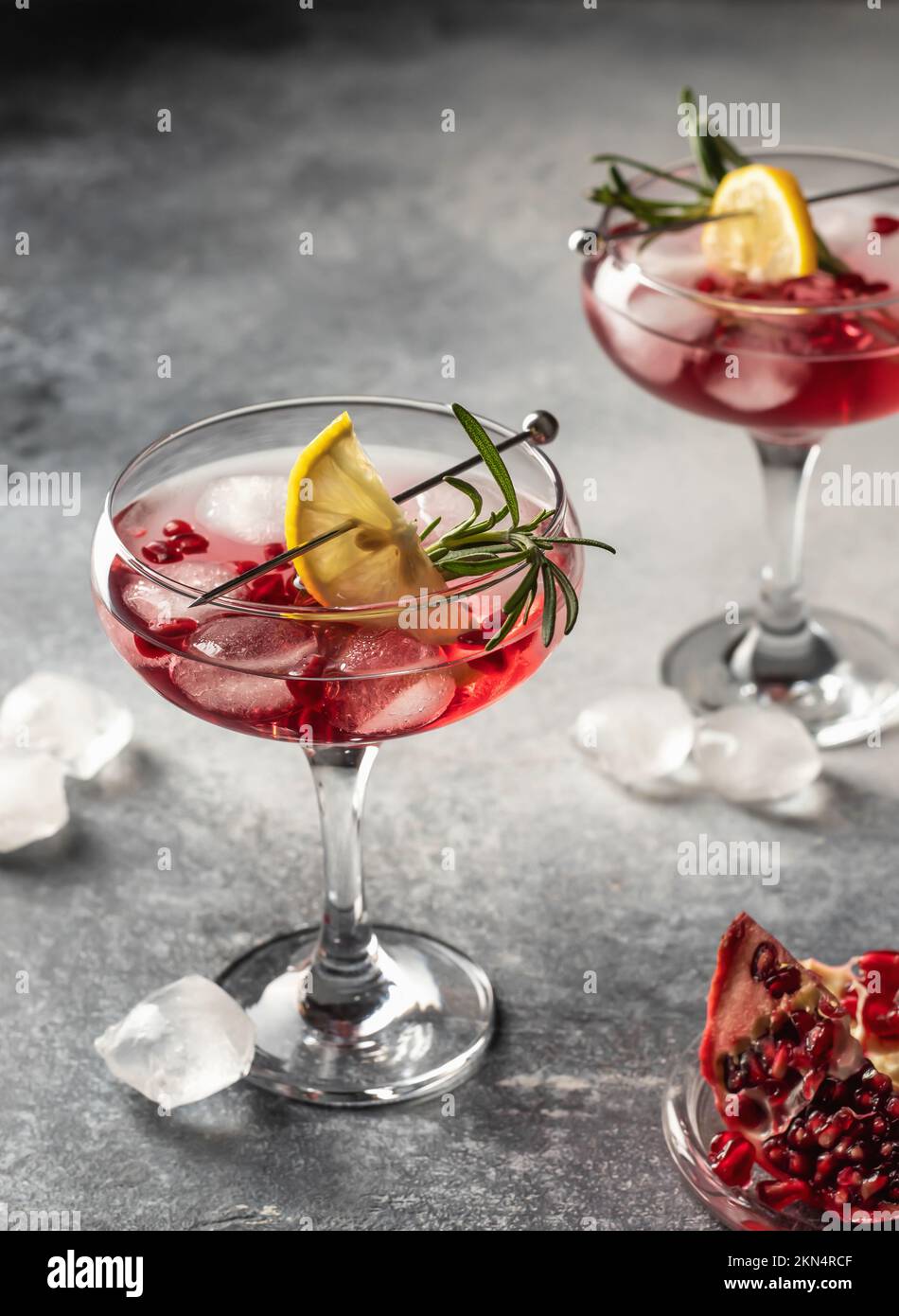 Two glasses of Pomegranate Christmas iced cocktail with rosemary and